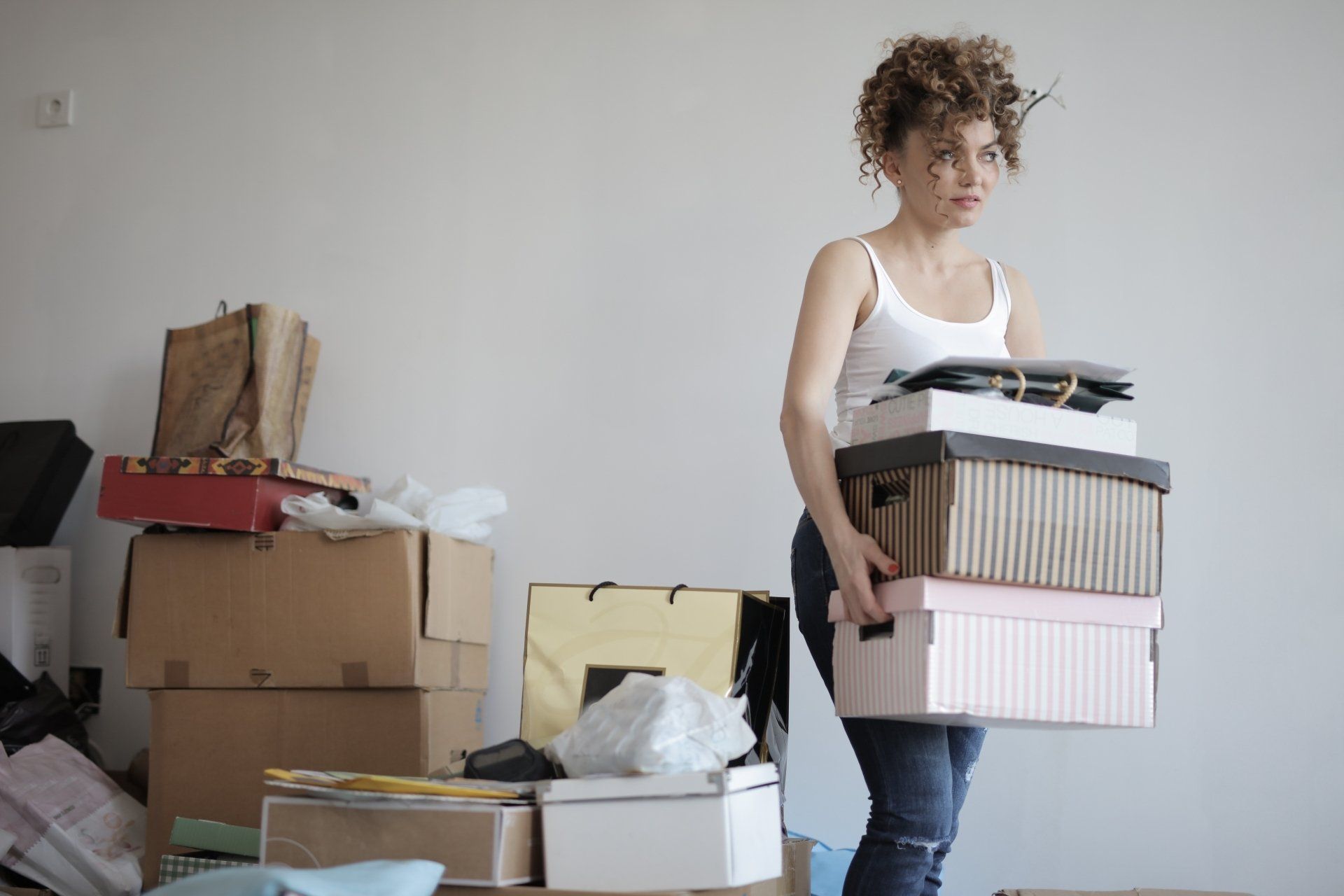 a woman is carrying a pile of boxes in a room