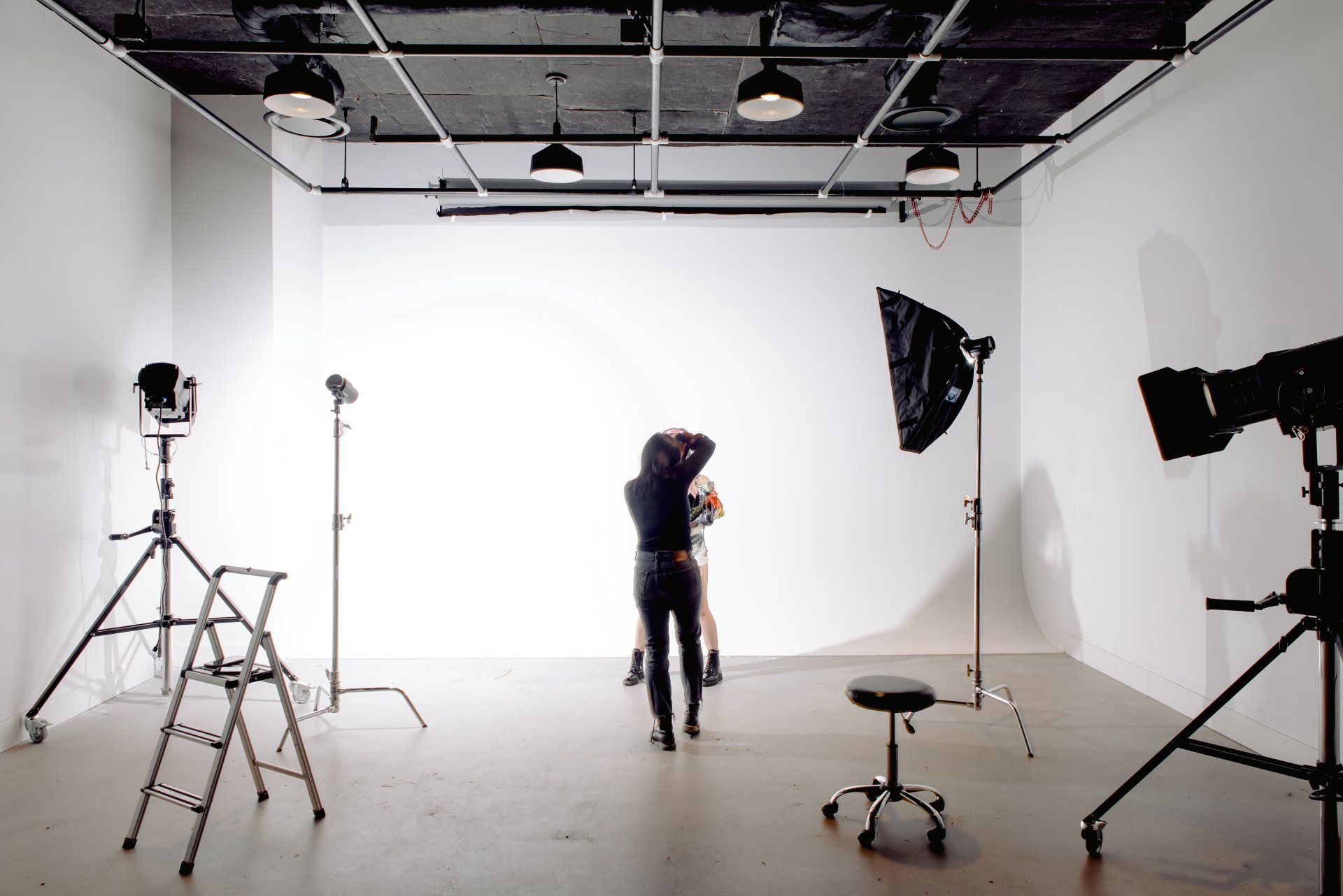 A woman is standing in front of a white wall in a photo studio