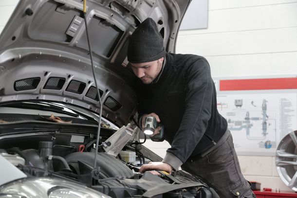 a man is working on the engine of a car with the hood open .
