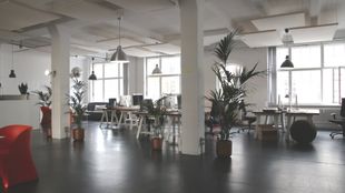 A large office with lots of windows and tables and chairs