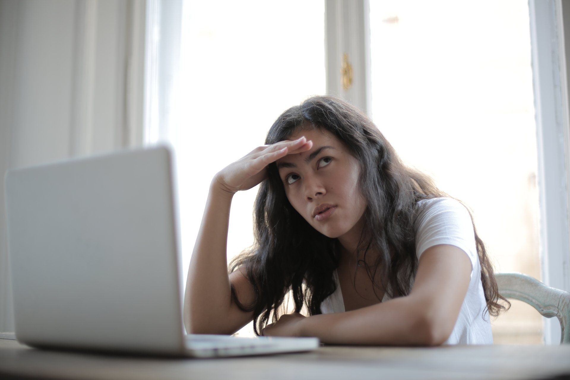 Woman anxiously awaits next steps at laptop.