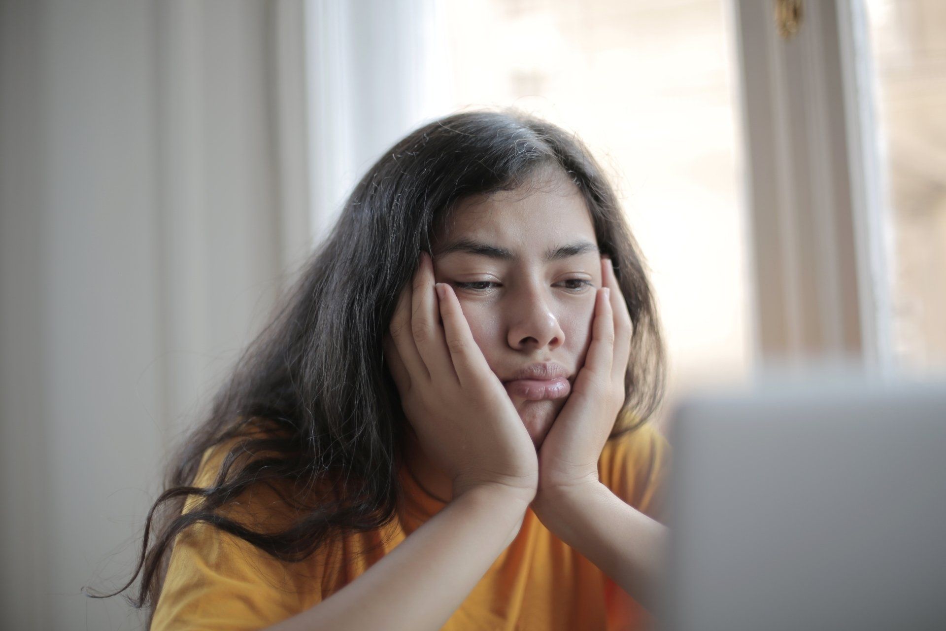 a woman is sitting in front of a laptop computer with her hands on her face