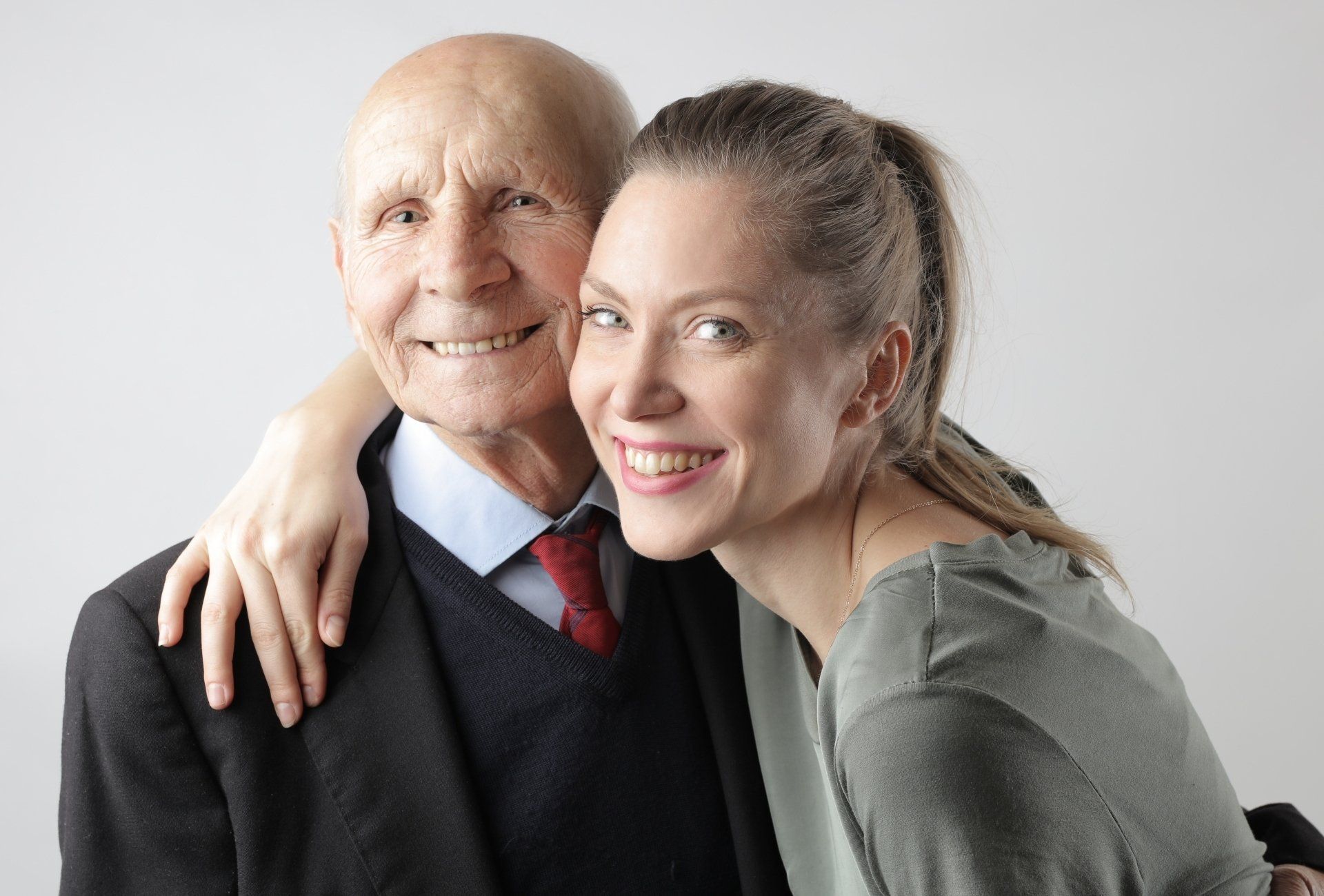 a young woman is hugging an older man in a suit and tie .