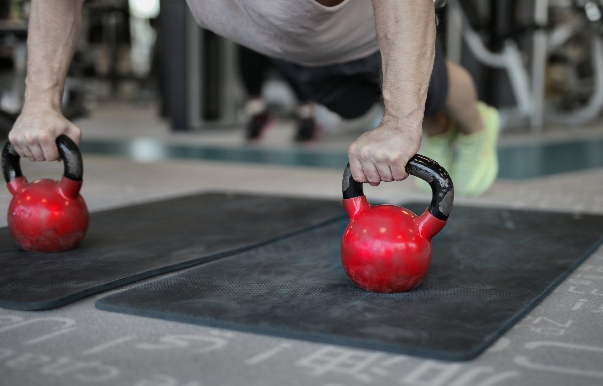 een man doet push-ups met een kettlebell in een sportschool.
