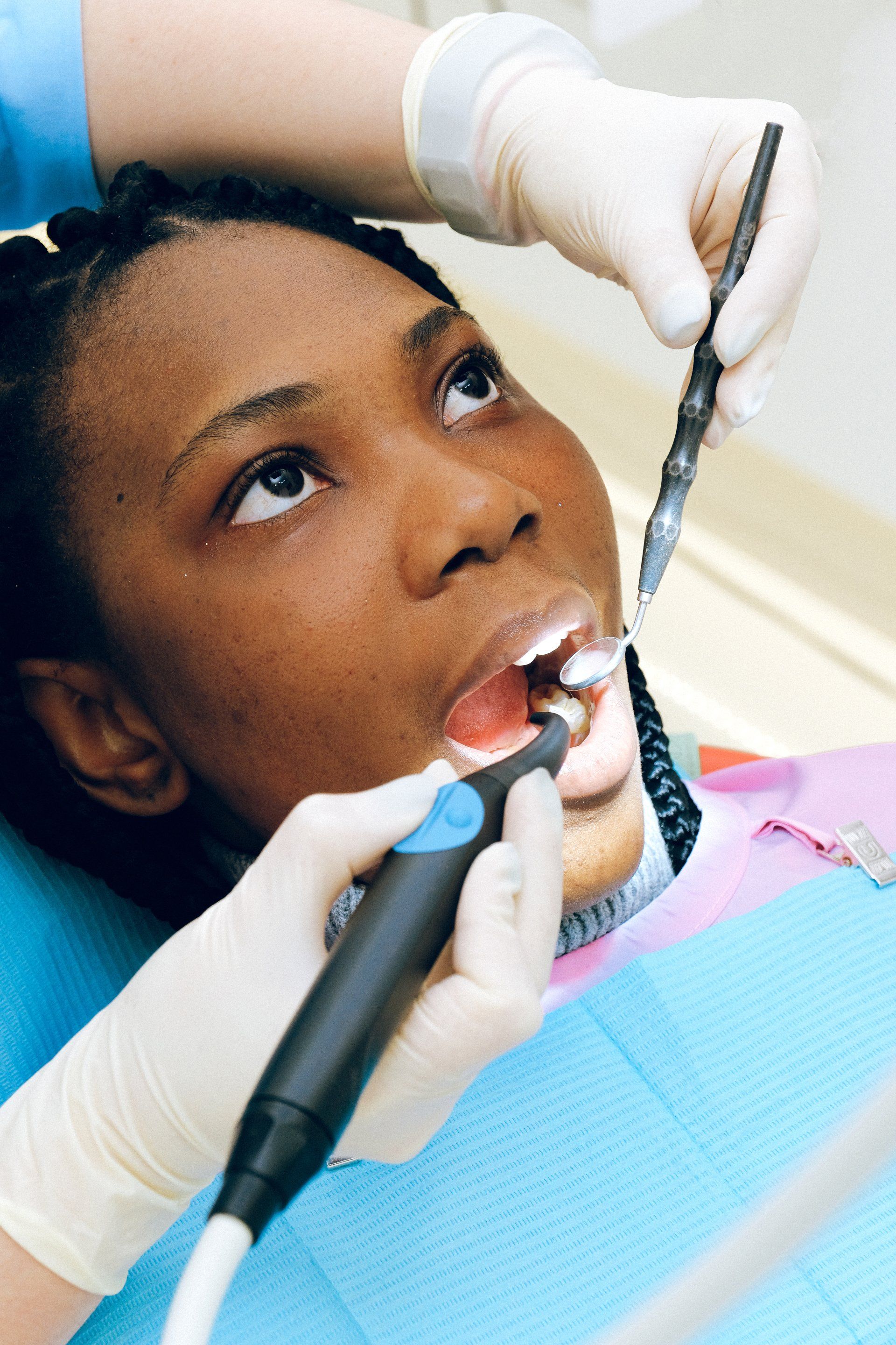 a woman is getting her teeth examined by a dentist