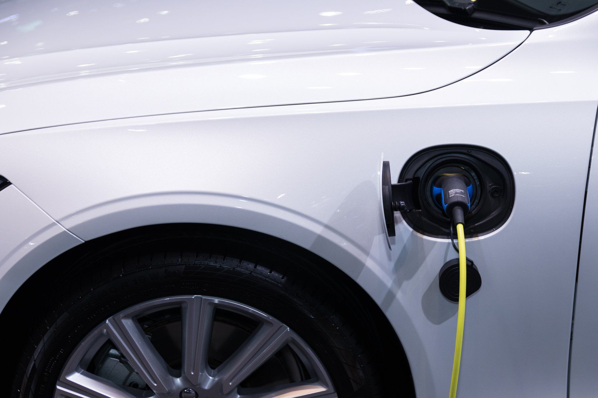 A white electric car is being charged with yellow ccs connector