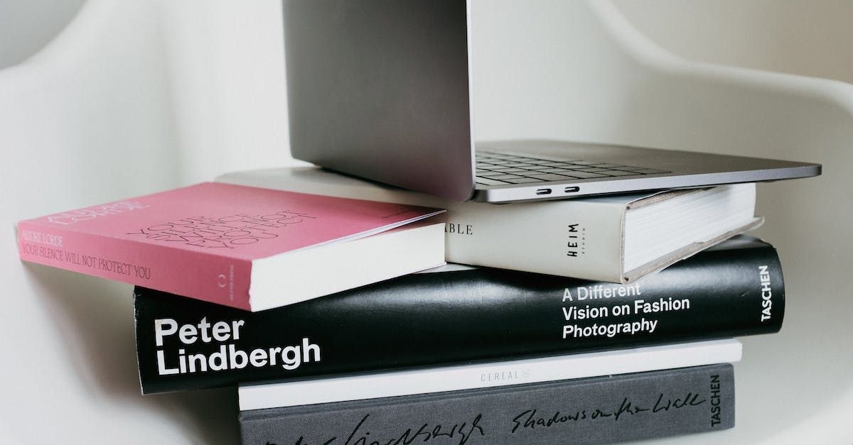 A laptop is sitting on top of a stack of books.