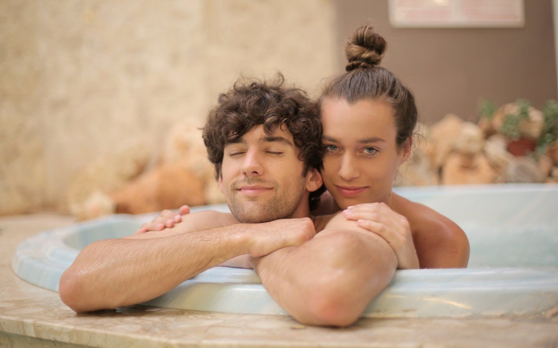 A man and a woman are taking a bath together in a jacuzzi.