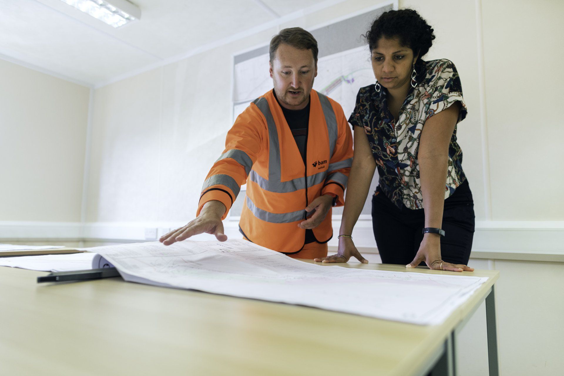 a man and a woman are looking at a blueprint on a table .