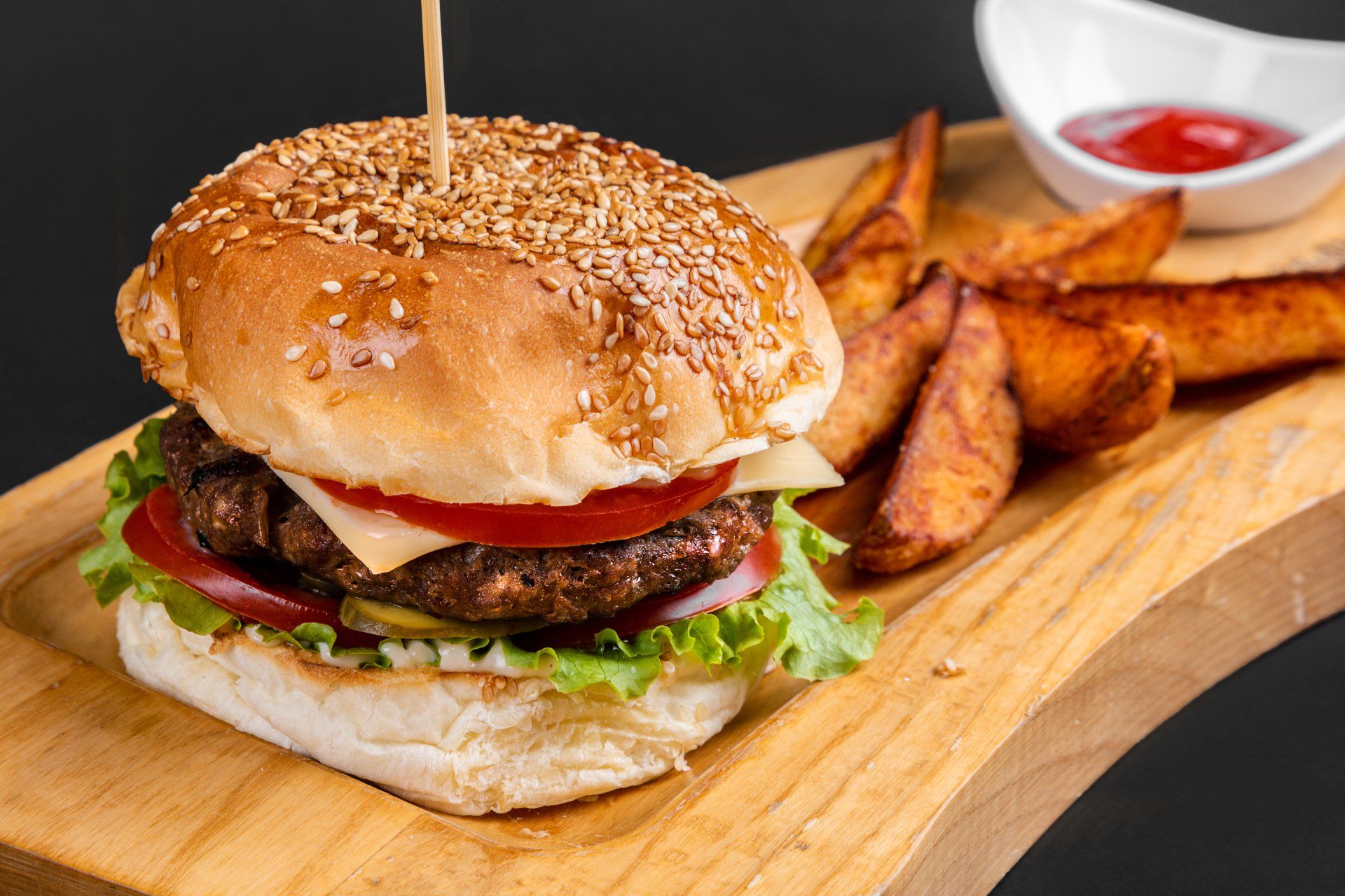 a hamburger and french fries on a wooden cutting board .