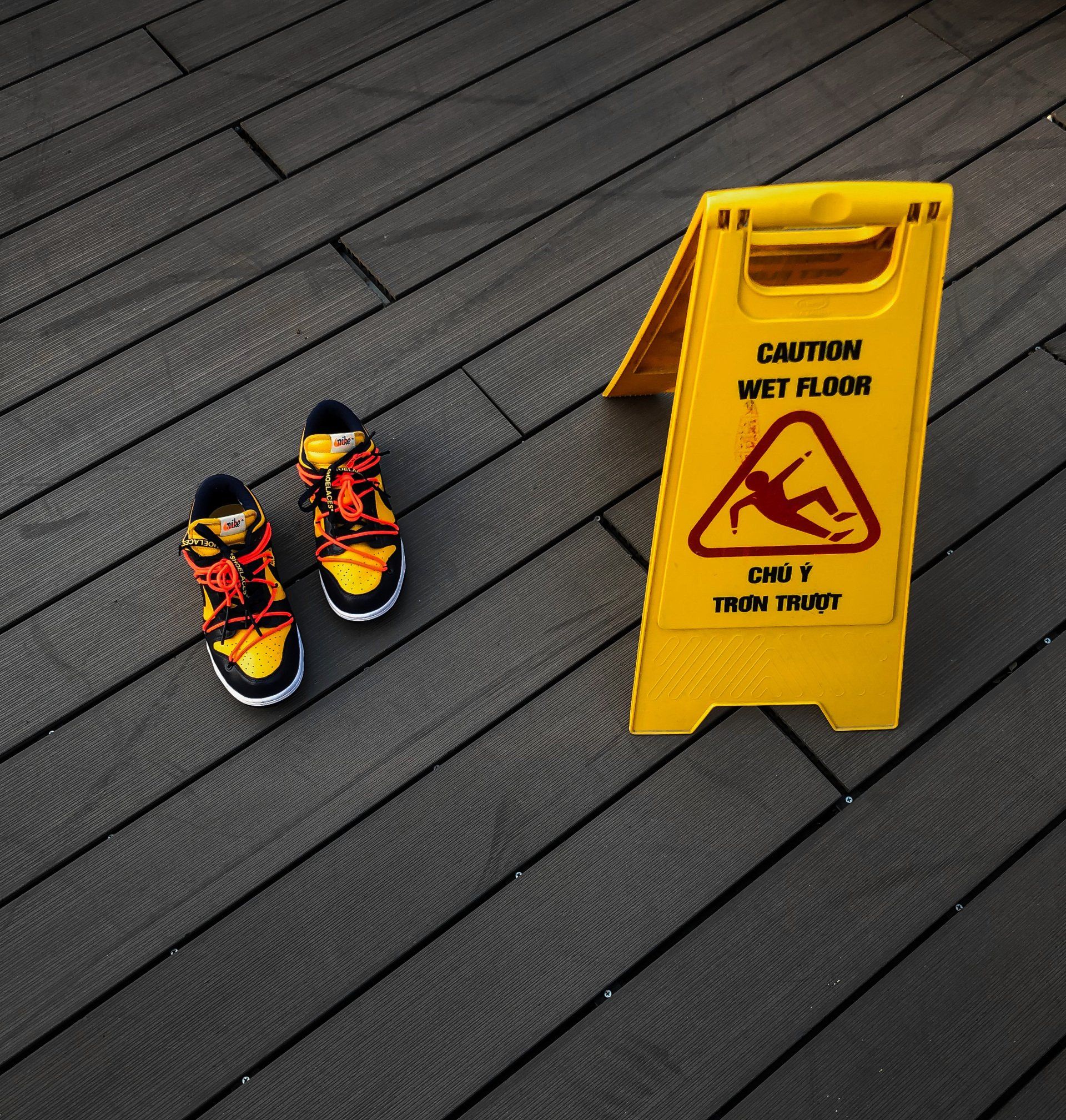 A pair of shoes next to a caution wet floor sign