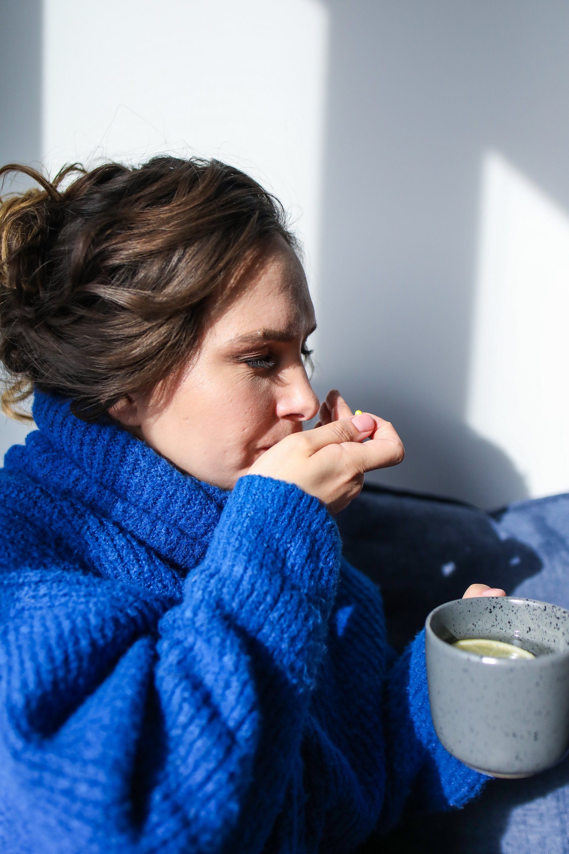 a woman in a blue sweater is holding a cup of tea