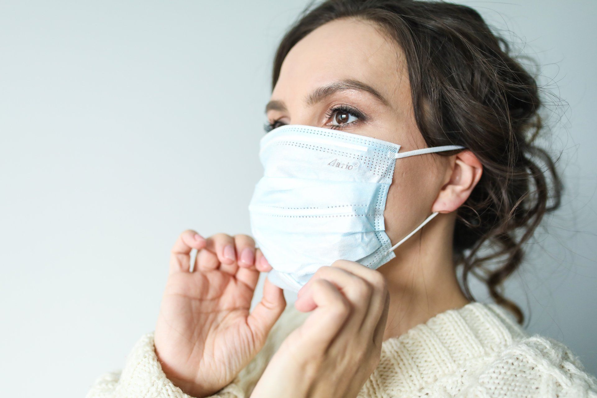 A woman is wearing a medical mask on her face.