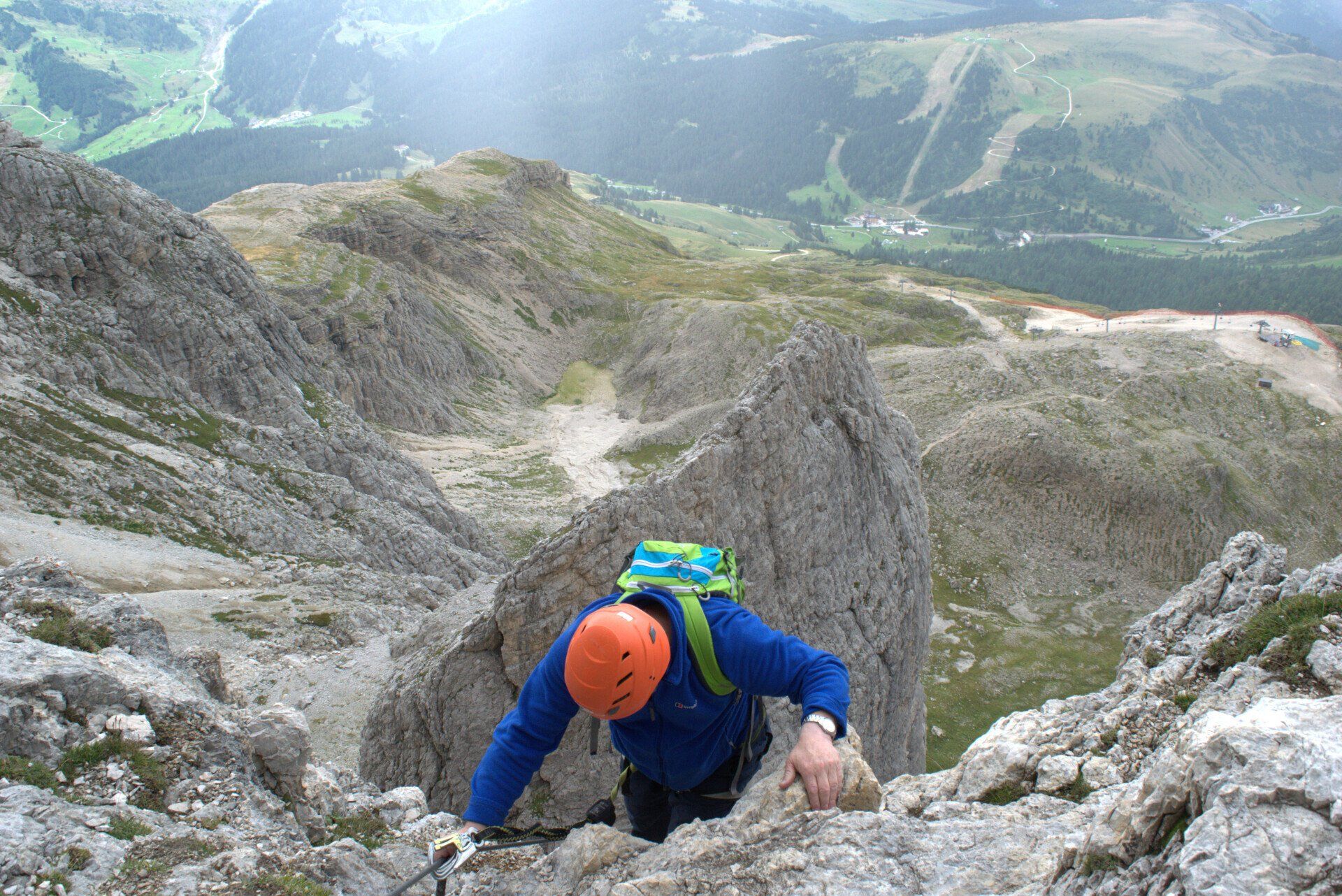 A man wearing a helmet is climbing up a mountain.