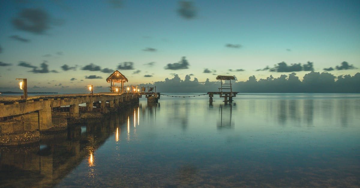 There is a dock in the middle of the ocean at sunset.