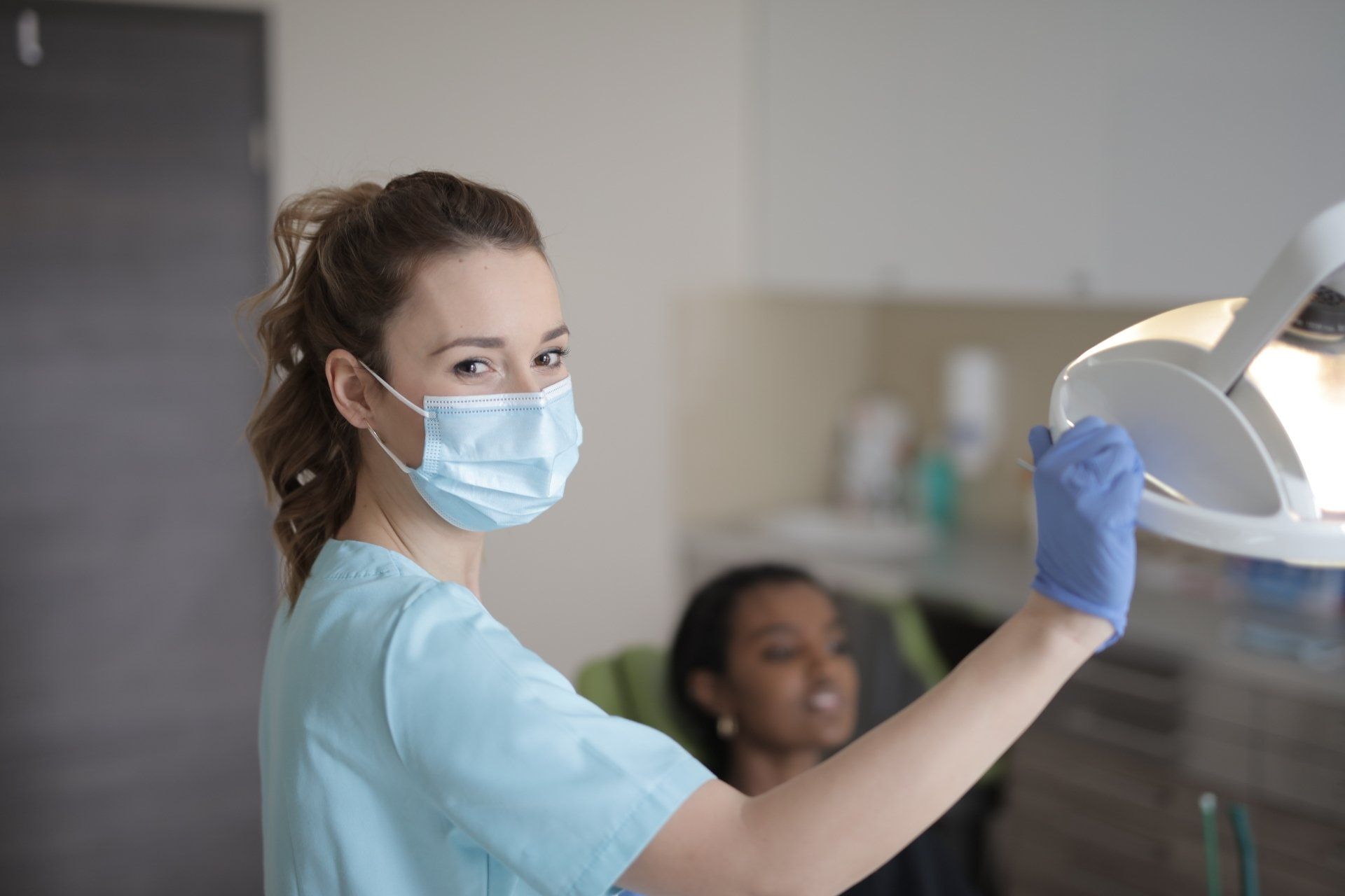 Dentist holding inspection light in dental office with patient out of focus in the background