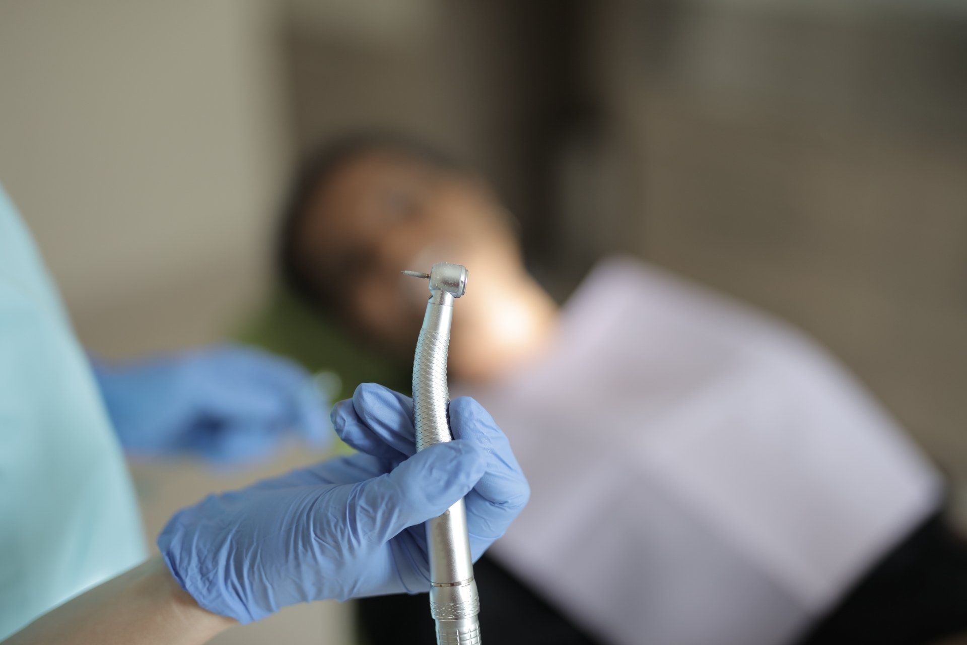 A dentist is holding a drill in front of a patient.