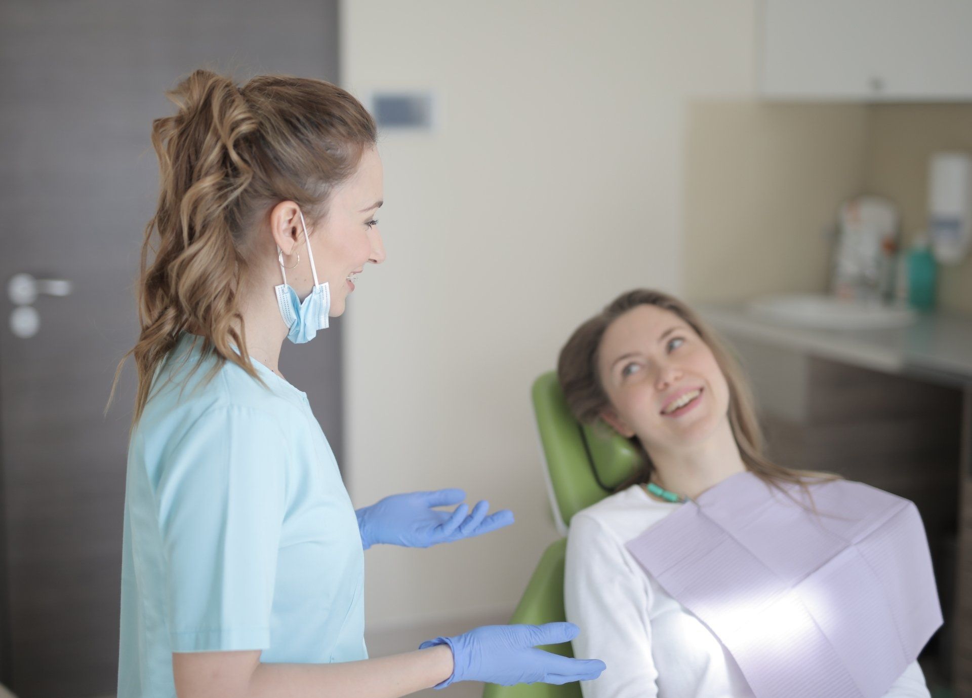 A woman is sitting in a dental chair talking to a dentist.