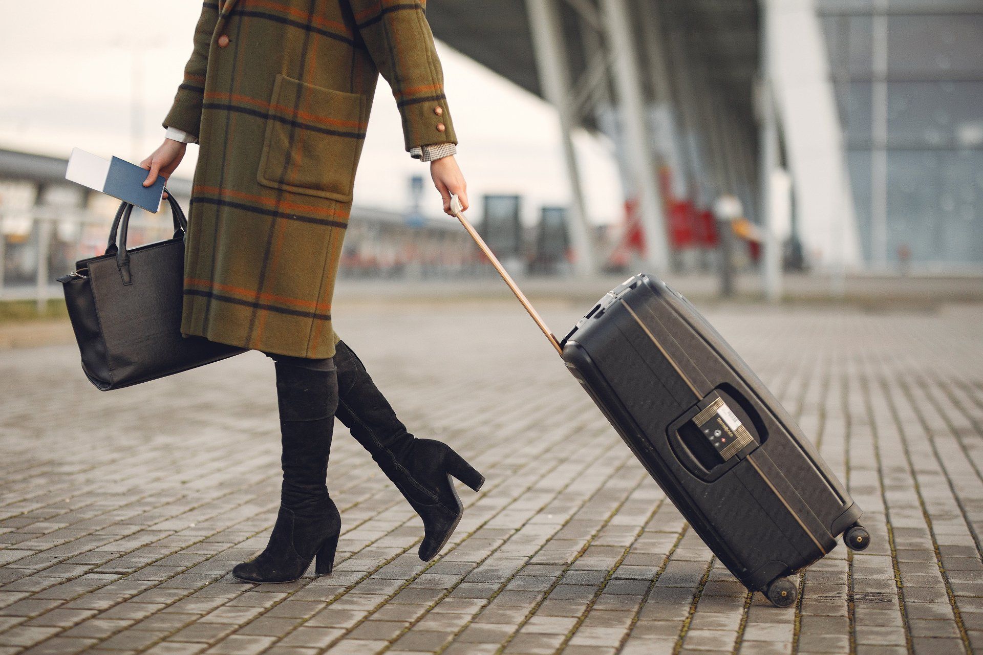 A woman is pulling a suitcase at an airport.