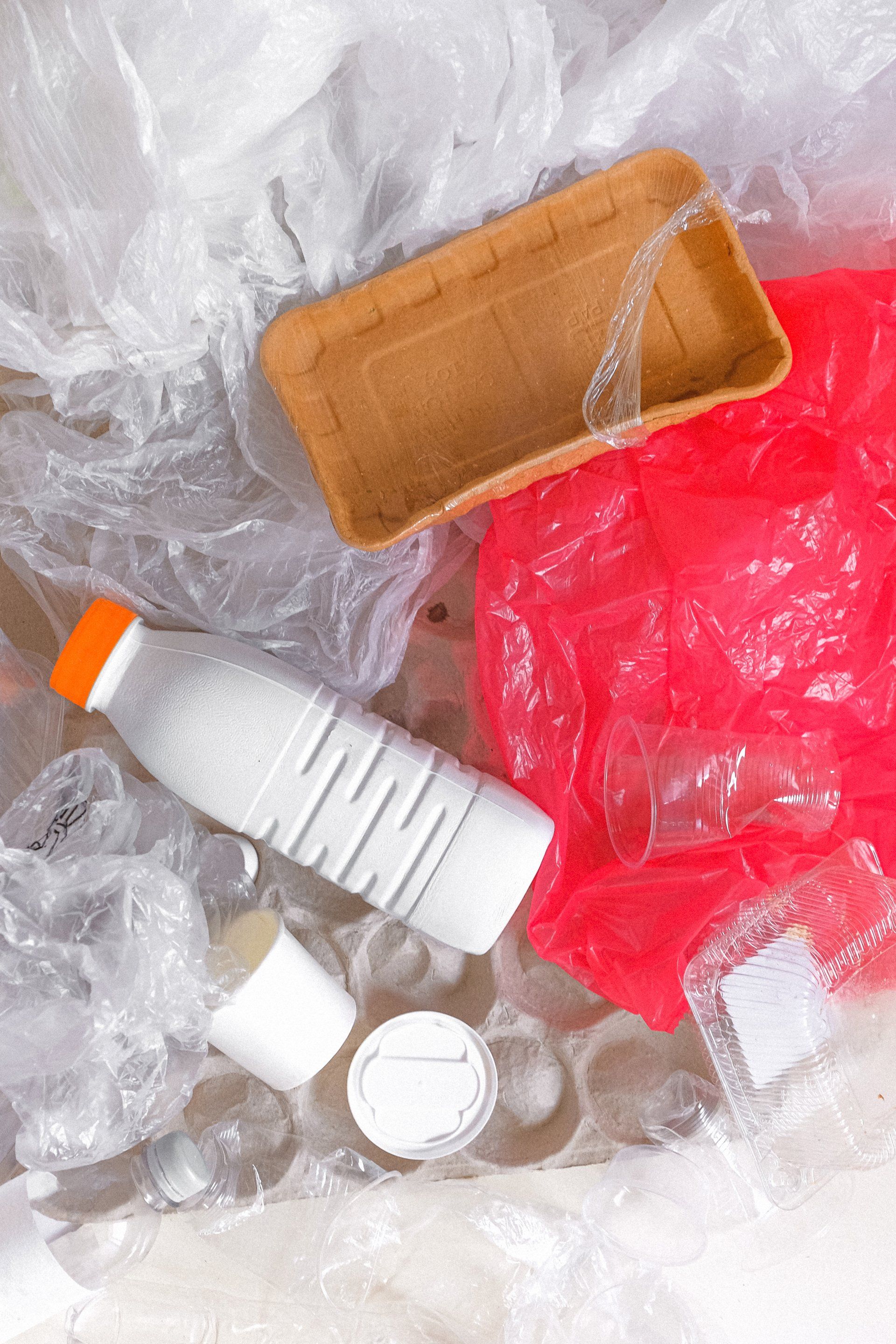 A pile of plastic bottles , plastic bags , and a wooden tray.