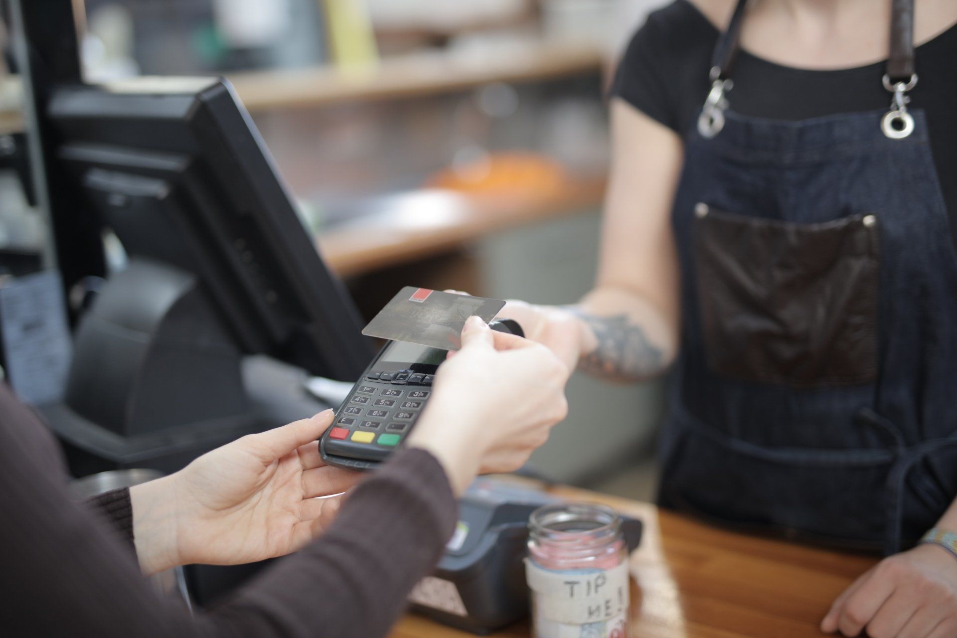 A woman is using a credit card to pay for a coffee.