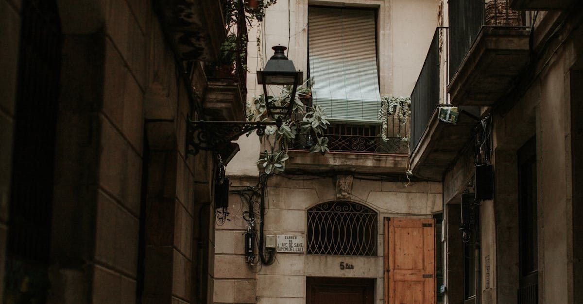 A narrow alleyway between two buildings with a lamp on the side of the building.