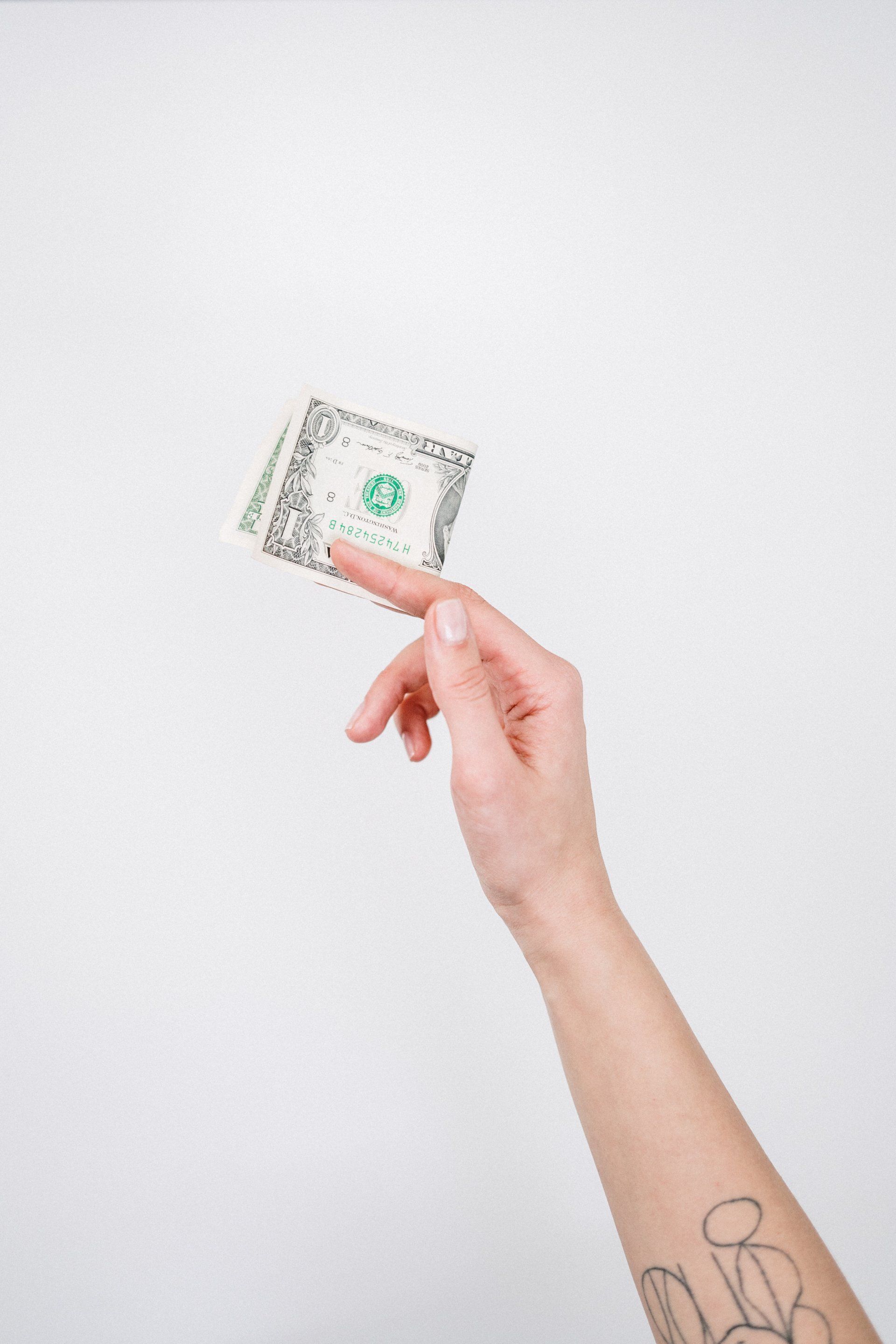 hand holding a folded dollar bill