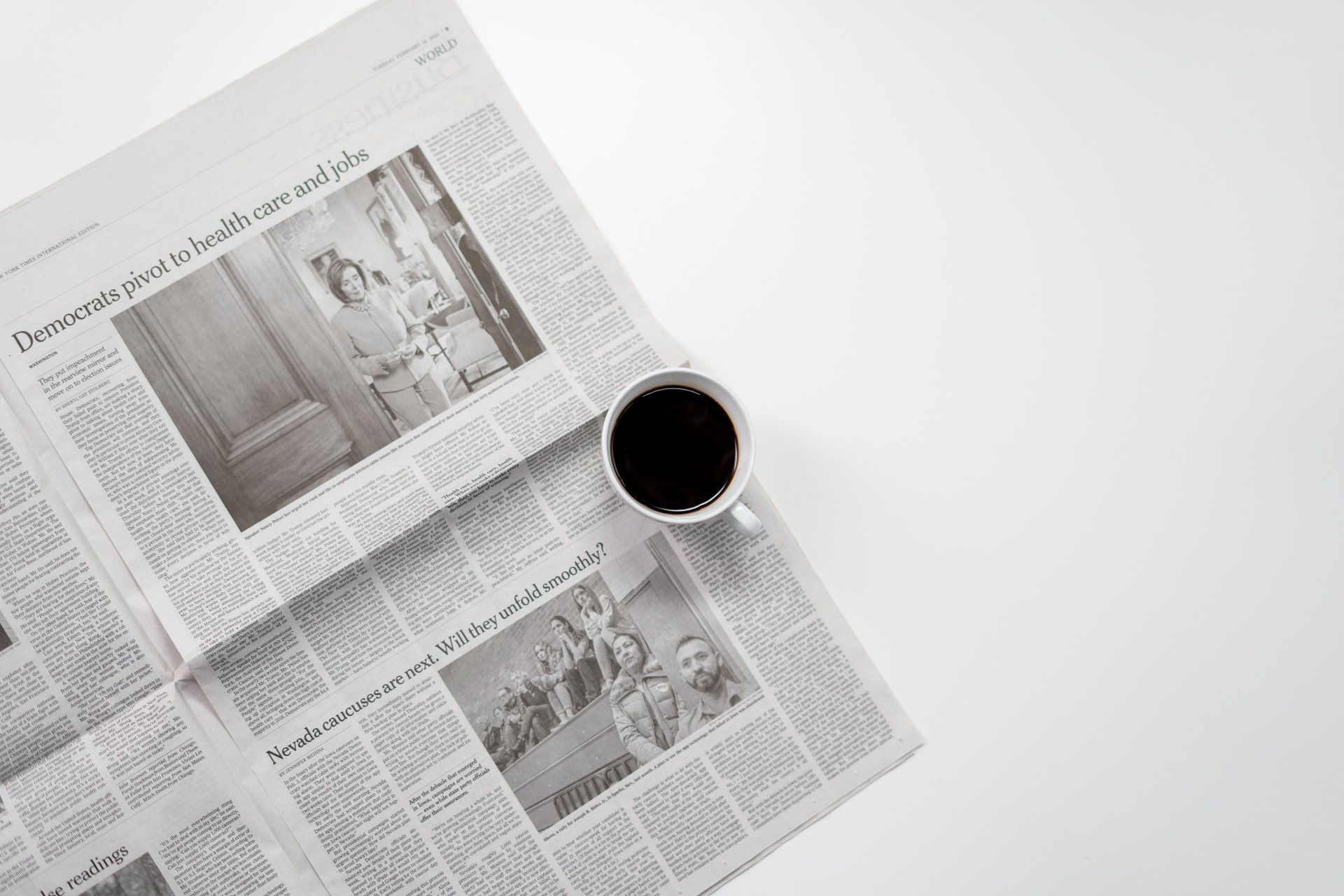a cup of coffee is sitting on top of an open newspaper .