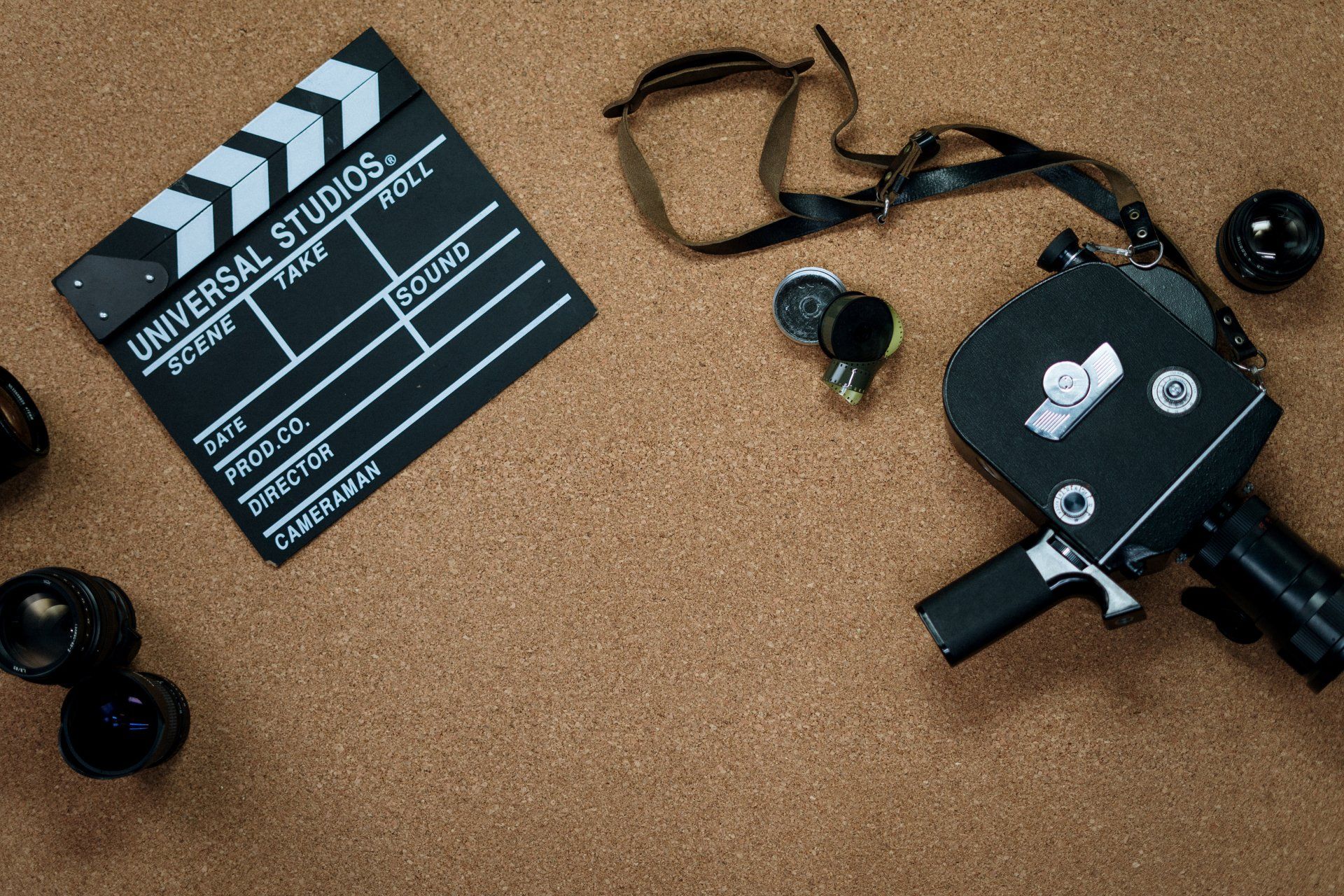 A clapper board and a camera are on a cork board.