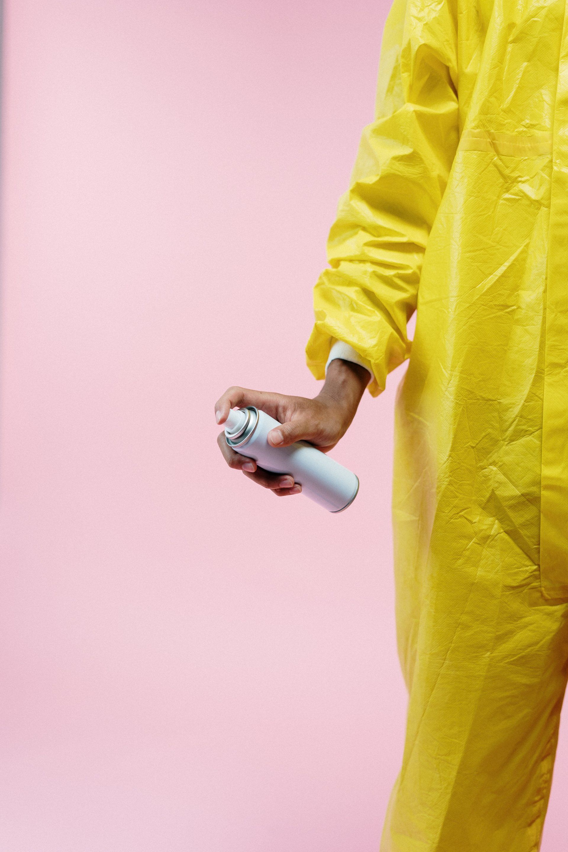 person in yellow lab coat with an aerosol can