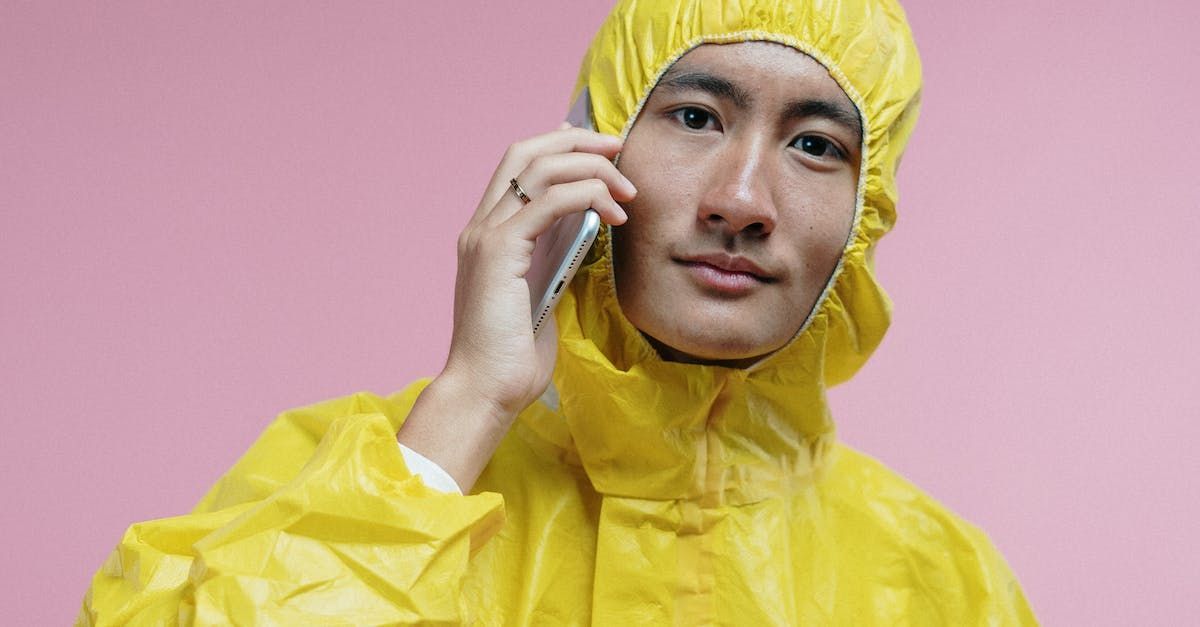 A man in a yellow protective suit is talking on a cell phone.