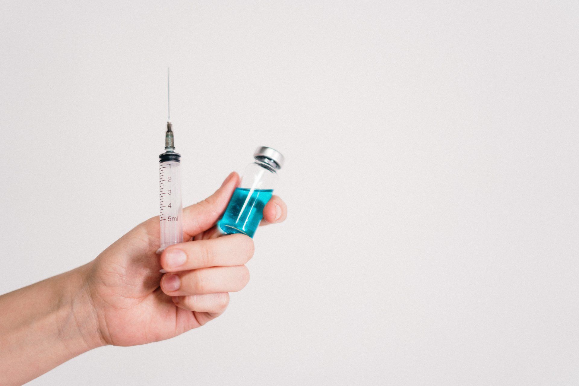 A person holding a syringe and a bottle of vaccine