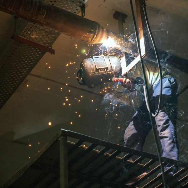 worker welding a metal pipe connected to a ceiling in Bozeman