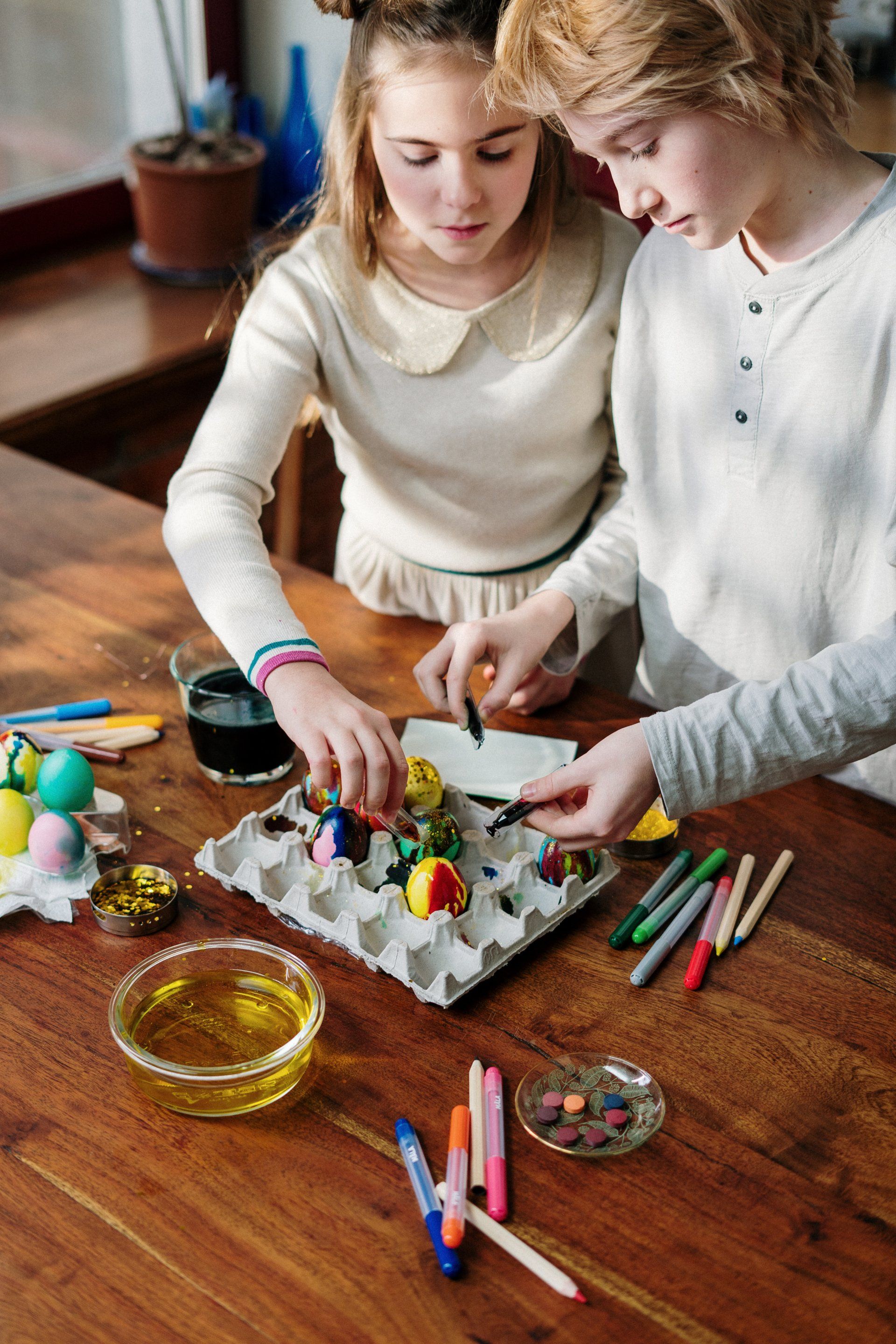An image of two children painting eggs as part of an activity. The focal point of the image is the egg decoration activity.