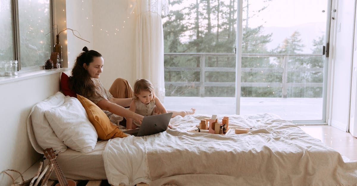 A woman and a child are sitting on a bed with a laptop.