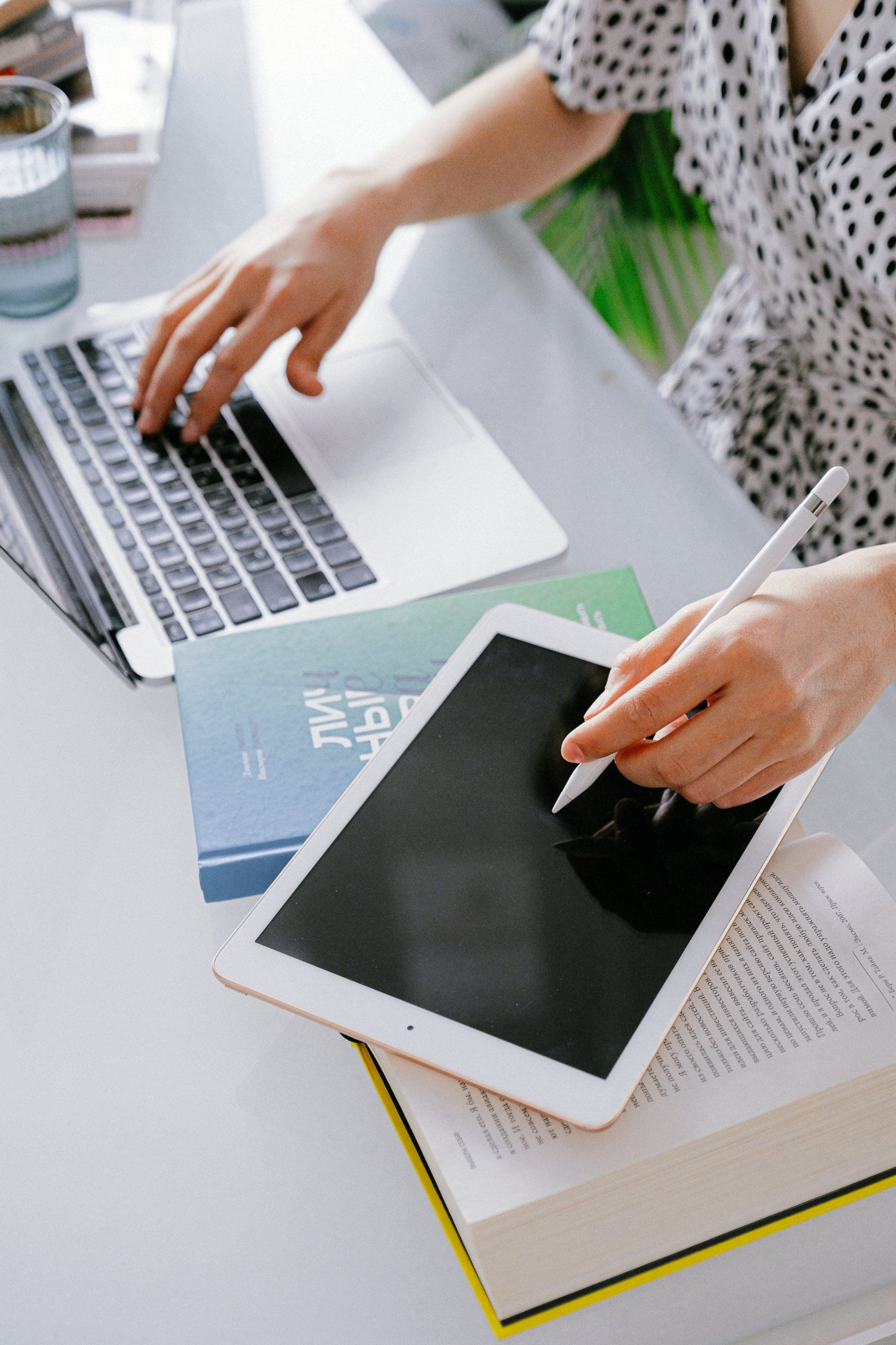 A woman is using a laptop and a tablet at the same time.
