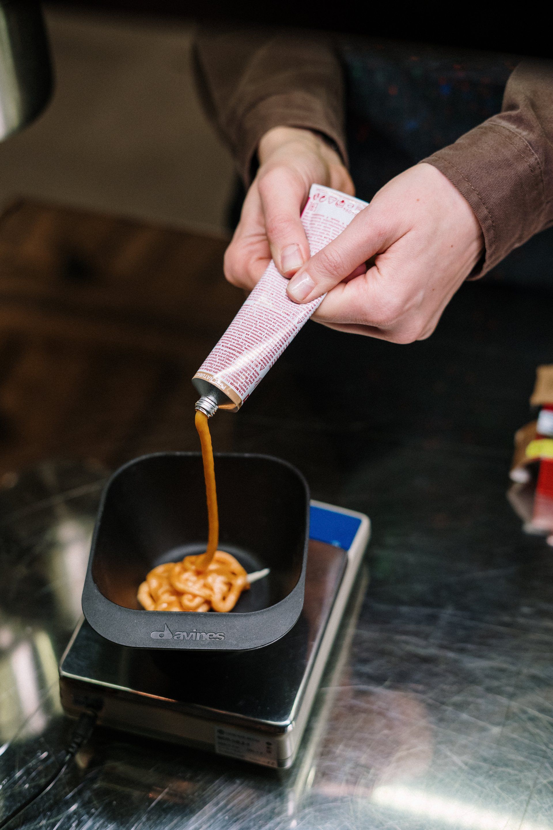 A person is pouring a tube of hair dye into a bowl.