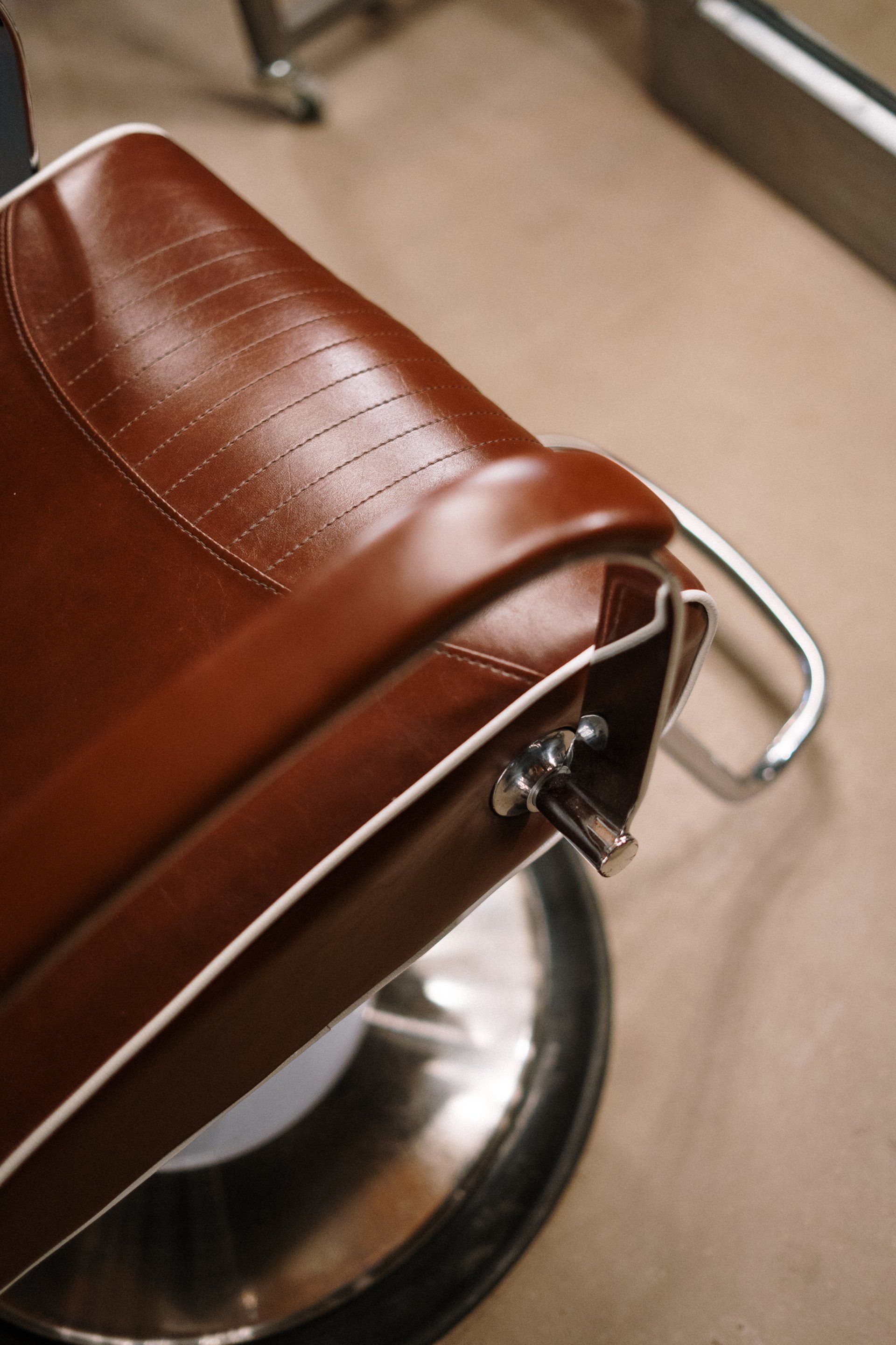 A close up of a brown leather barber chair in a barber shop.