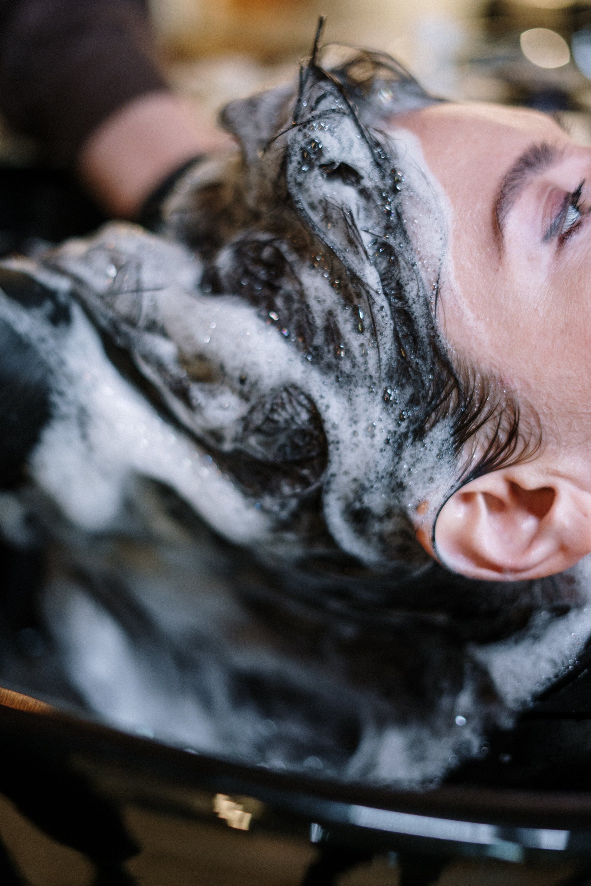 A woman is washing her hair in a sink at a salon.