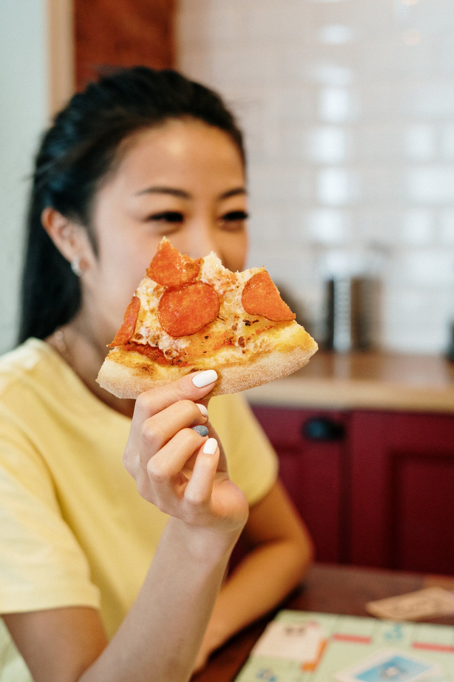 A woman is eating a slice of pepperoni pizza.