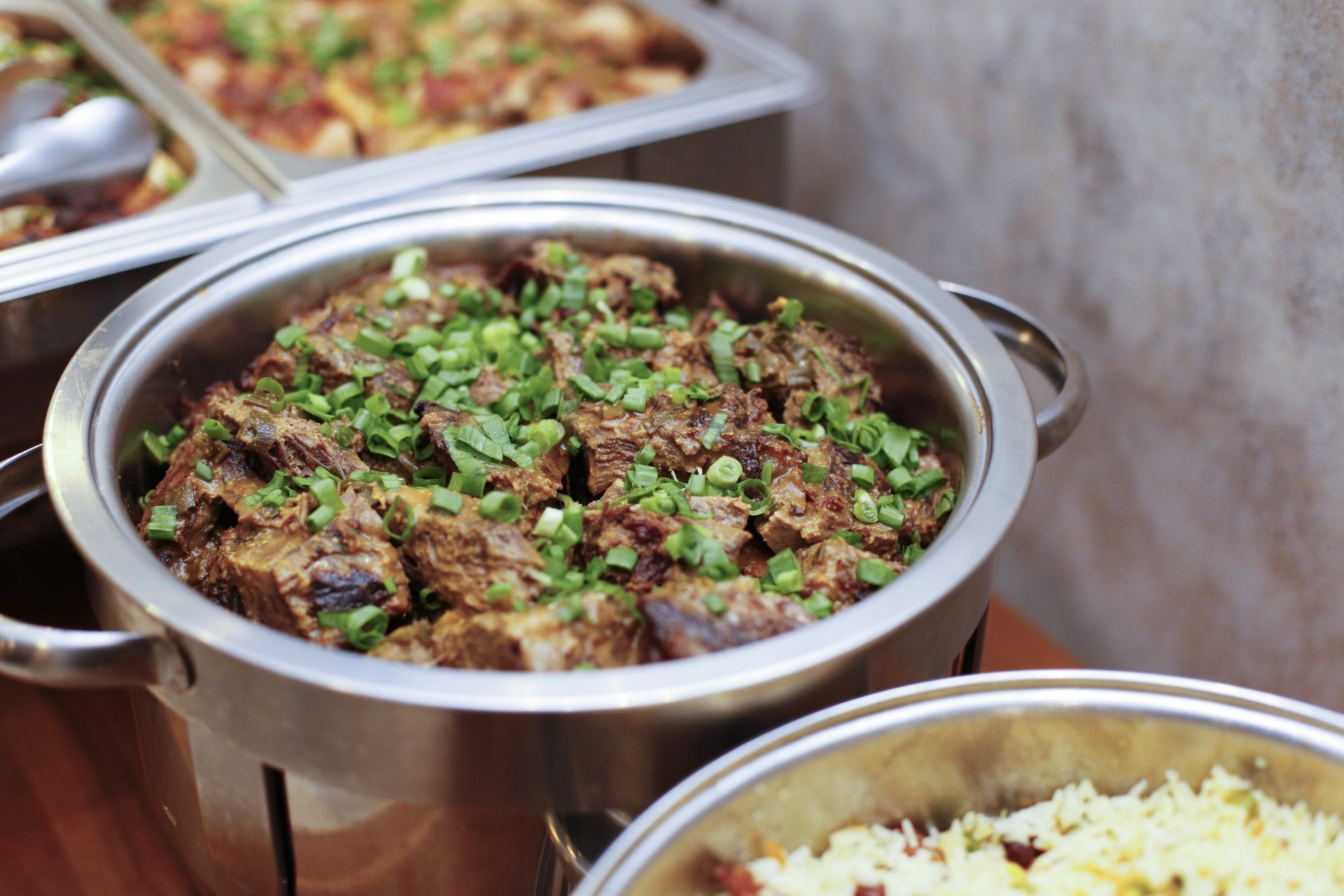 A buffet table with a bowl of meat and rice.