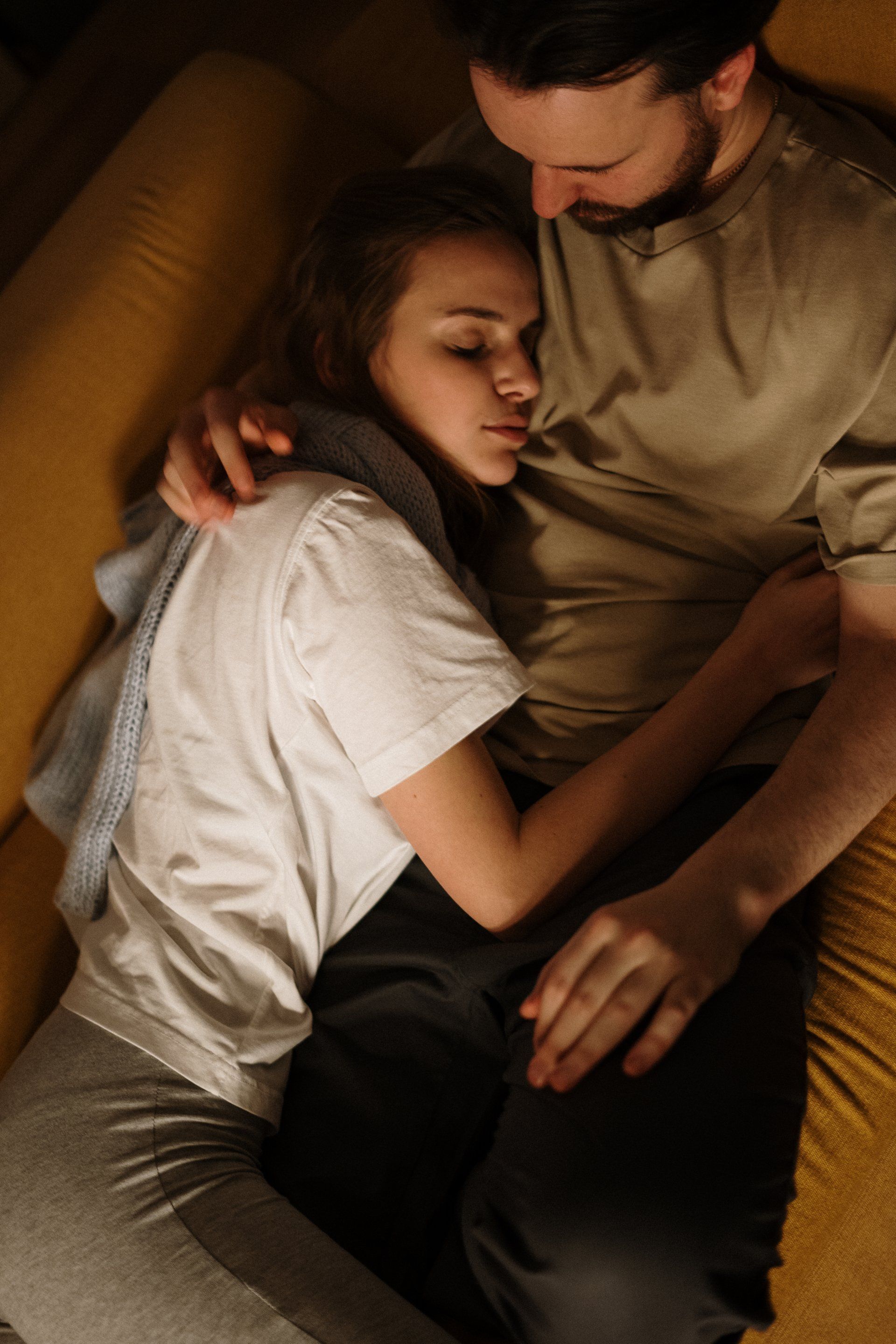 a man and a woman are laying on a couch hugging each other, co-regulating after a couples therapy session in Grapevine Texas