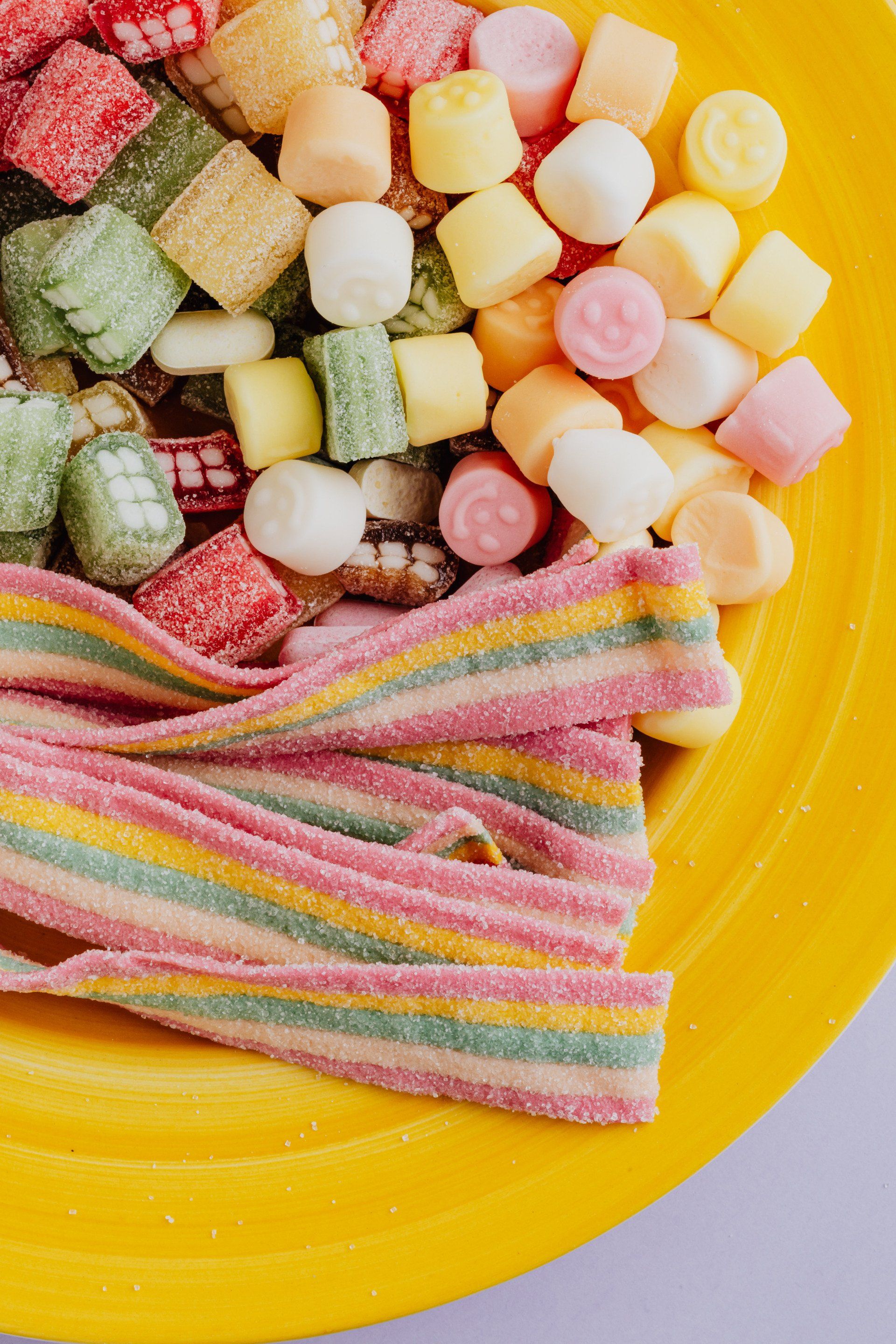 A yellow plate topped with a variety of candy and marshmallows.
