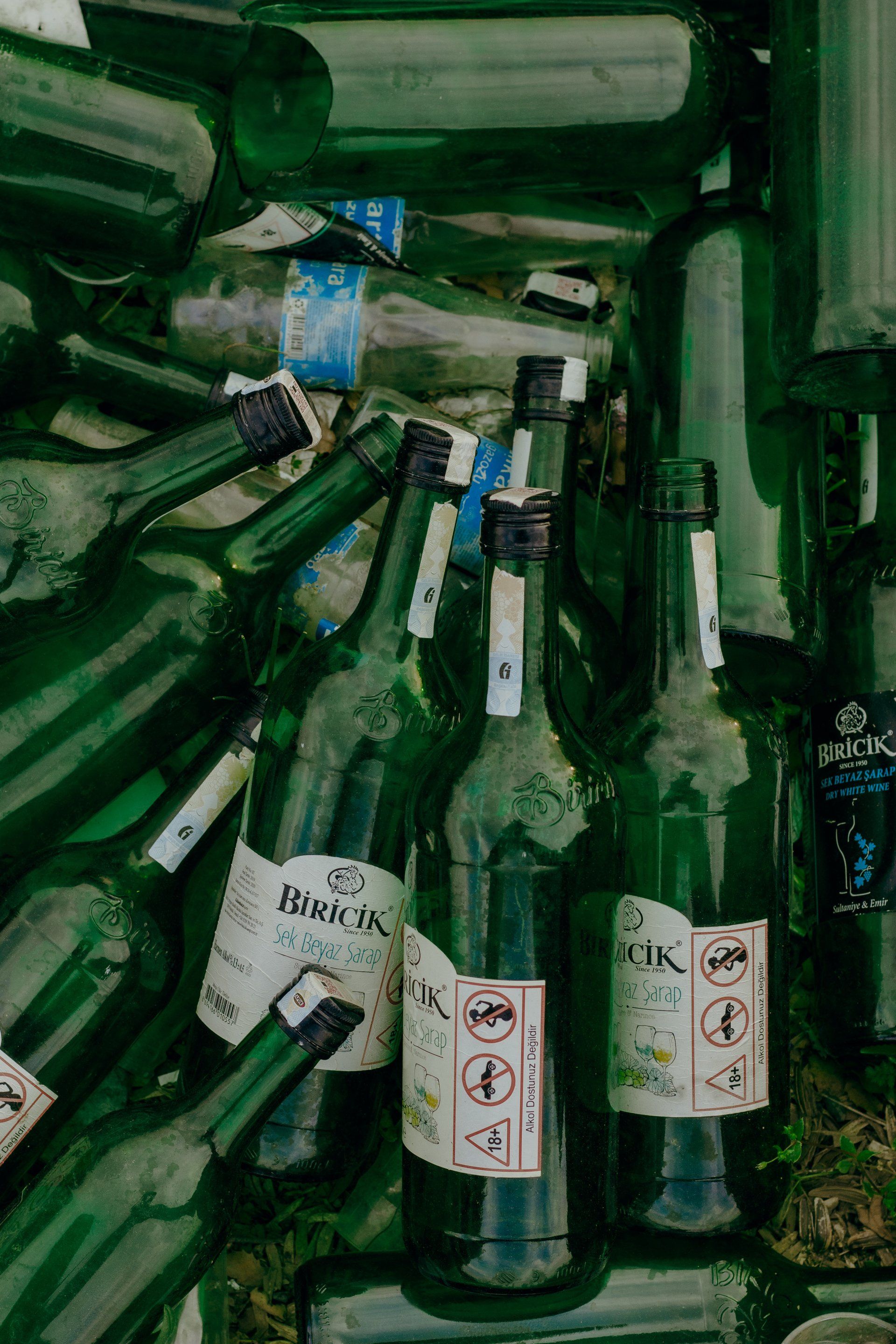Tall green glass bottles piled up in a confined area