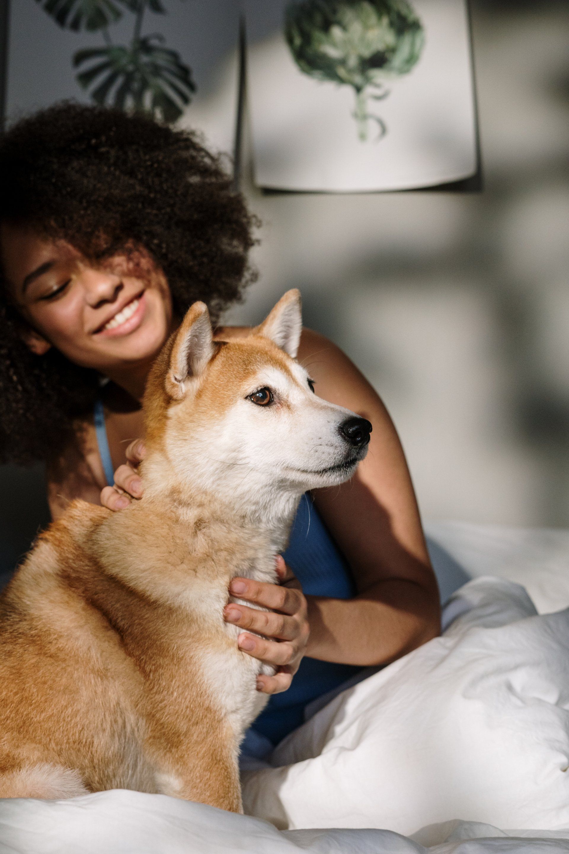 A woman is sitting on a bed holding a dog.