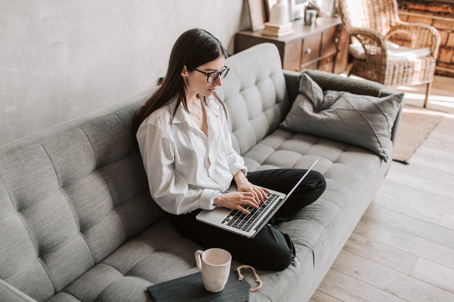 Woman working from home, sitting on her sofa with an open laptop on her lap