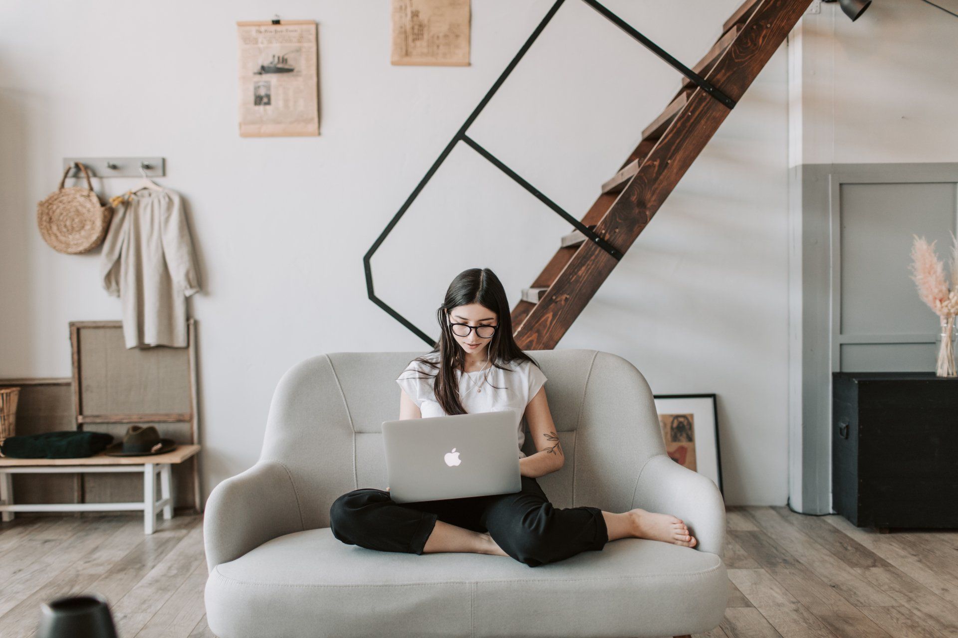 A woman is sitting on a couch using a laptop computer.