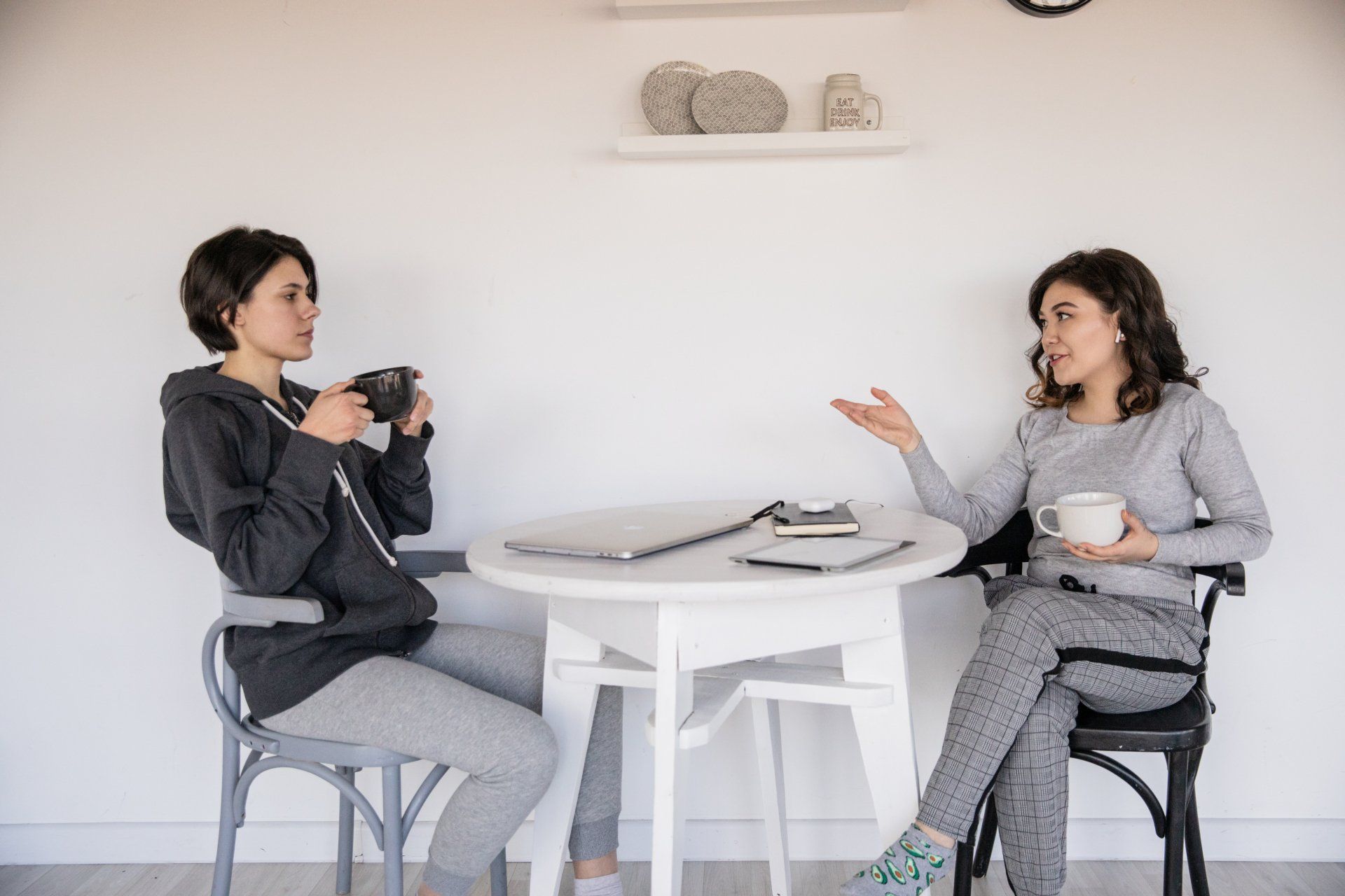 Two women sitting at a table talking and drinking coffee