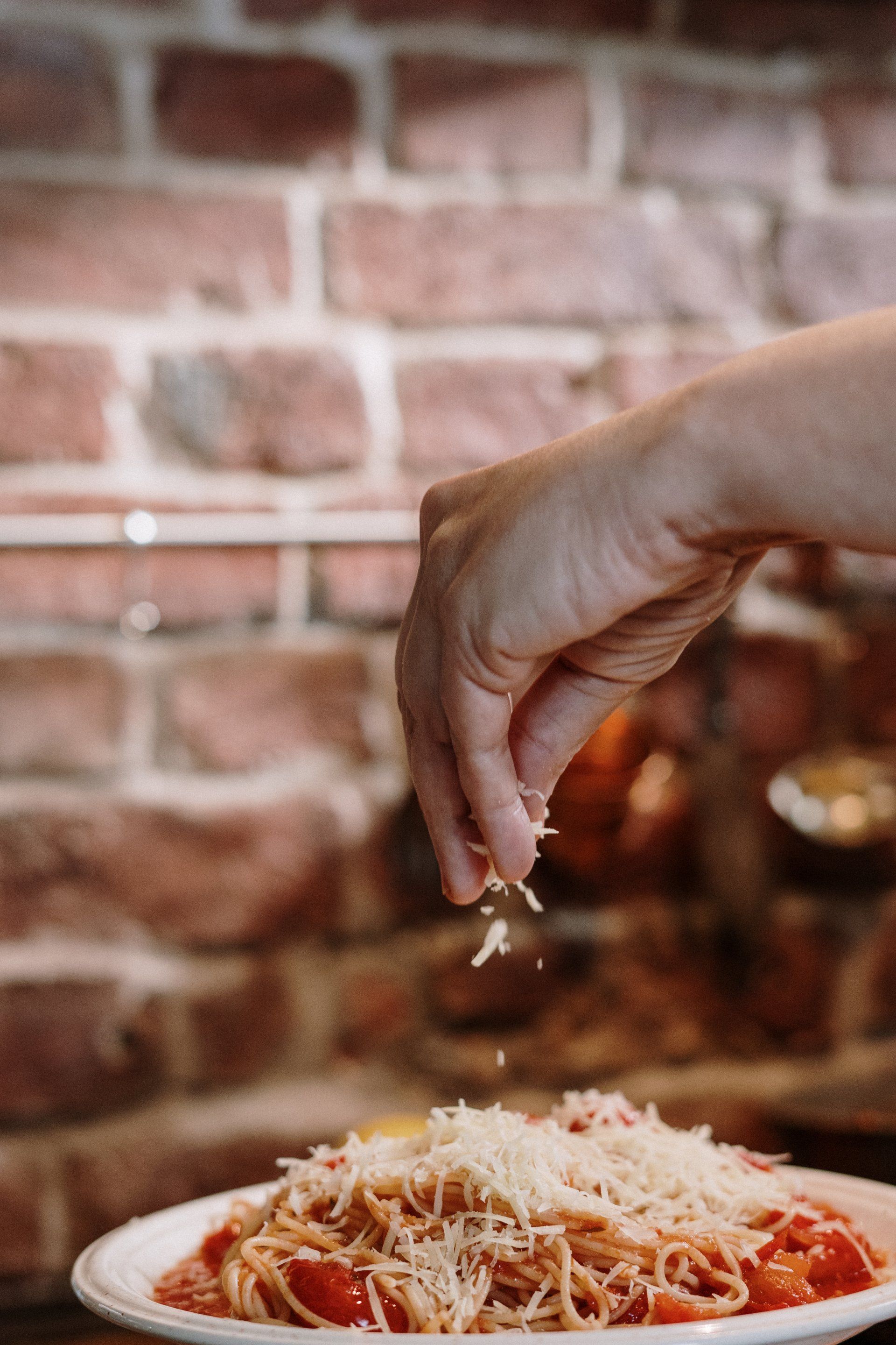 a person is sprinkling cheese on a plate of spaghetti .