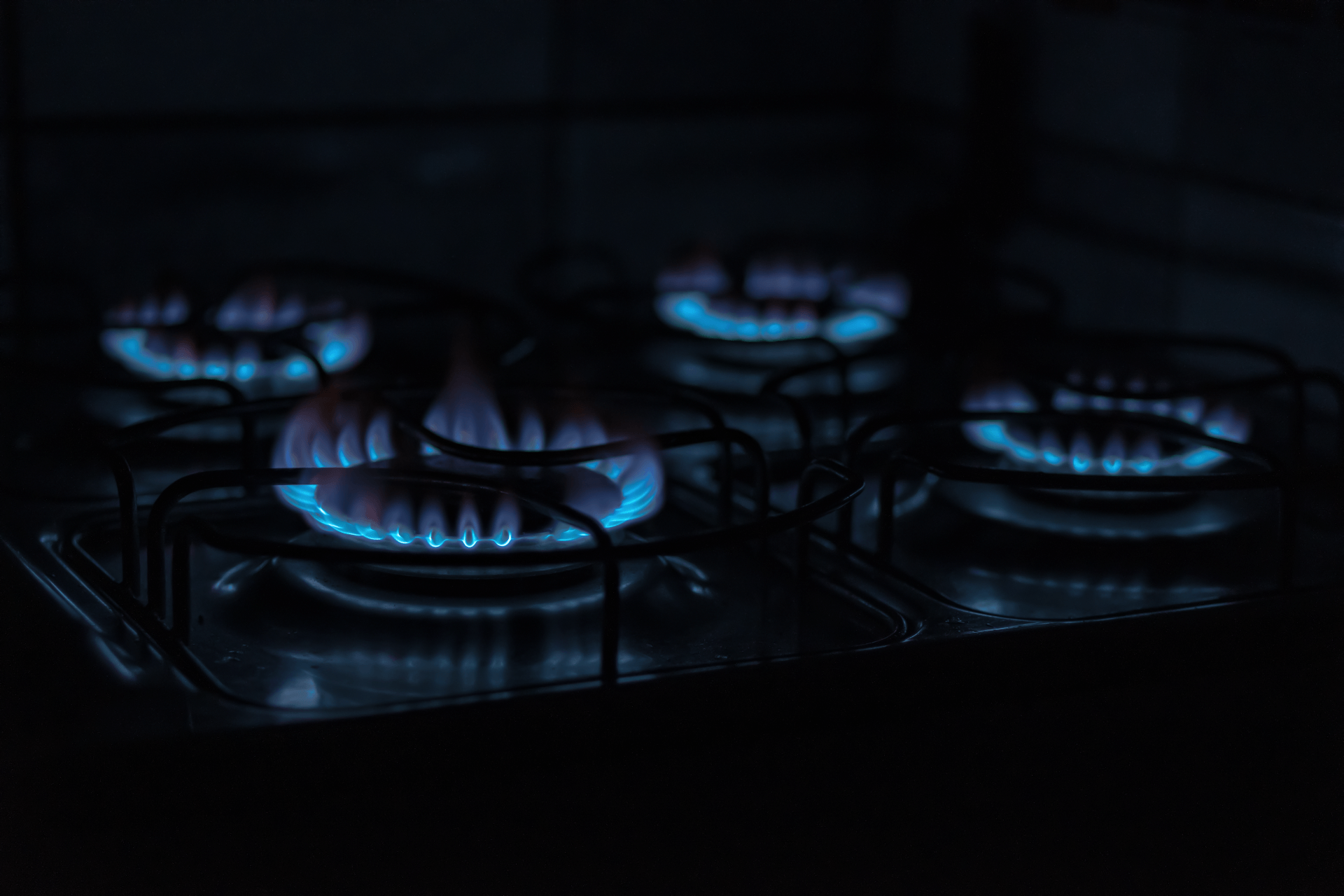 a close up of a gas stove with blue flames in the dark .